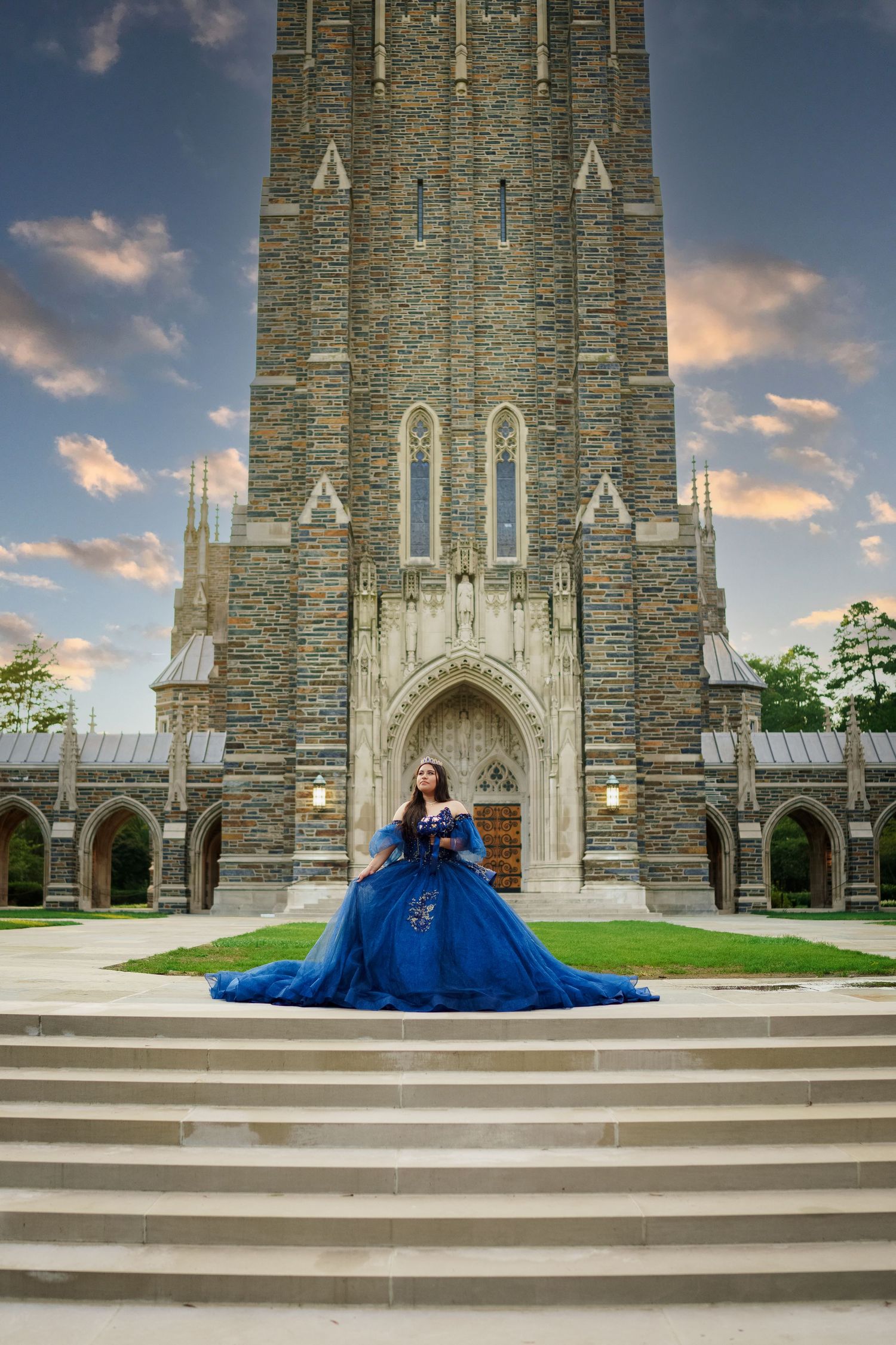 A stunning blue ball gown portrait on the steps of a Gothic stone cathedral at dusk.