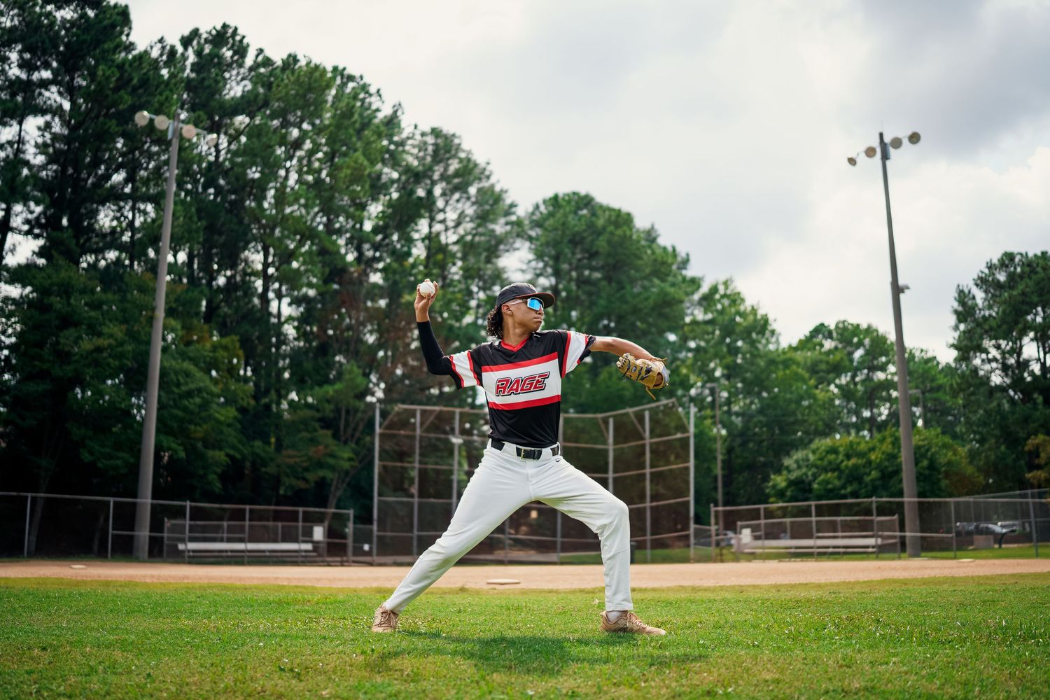 Baseball player in striped uniform winds up for pitch on baseball diamond.