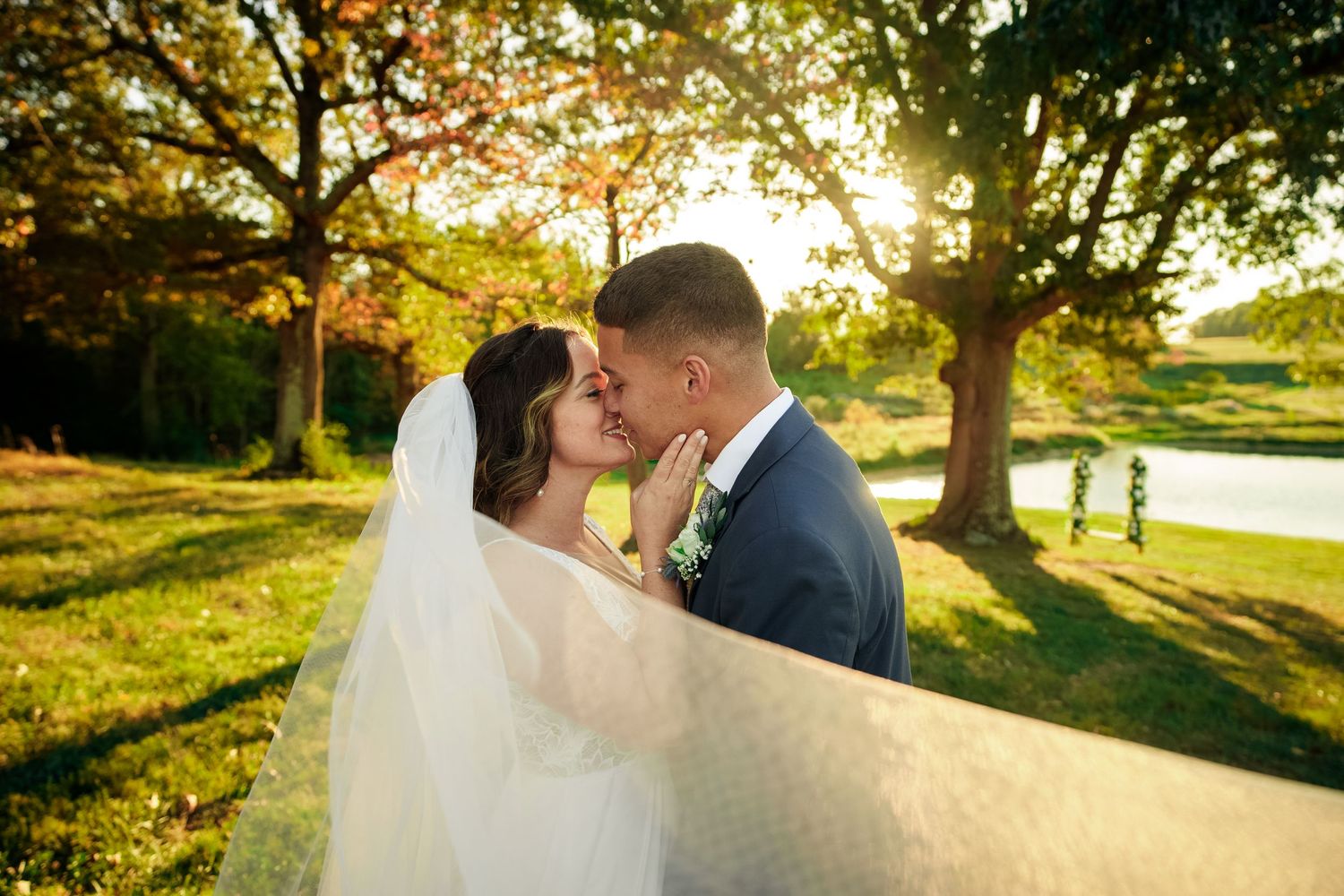 A romantic sunset wedding photo captured through a flowing white veil.