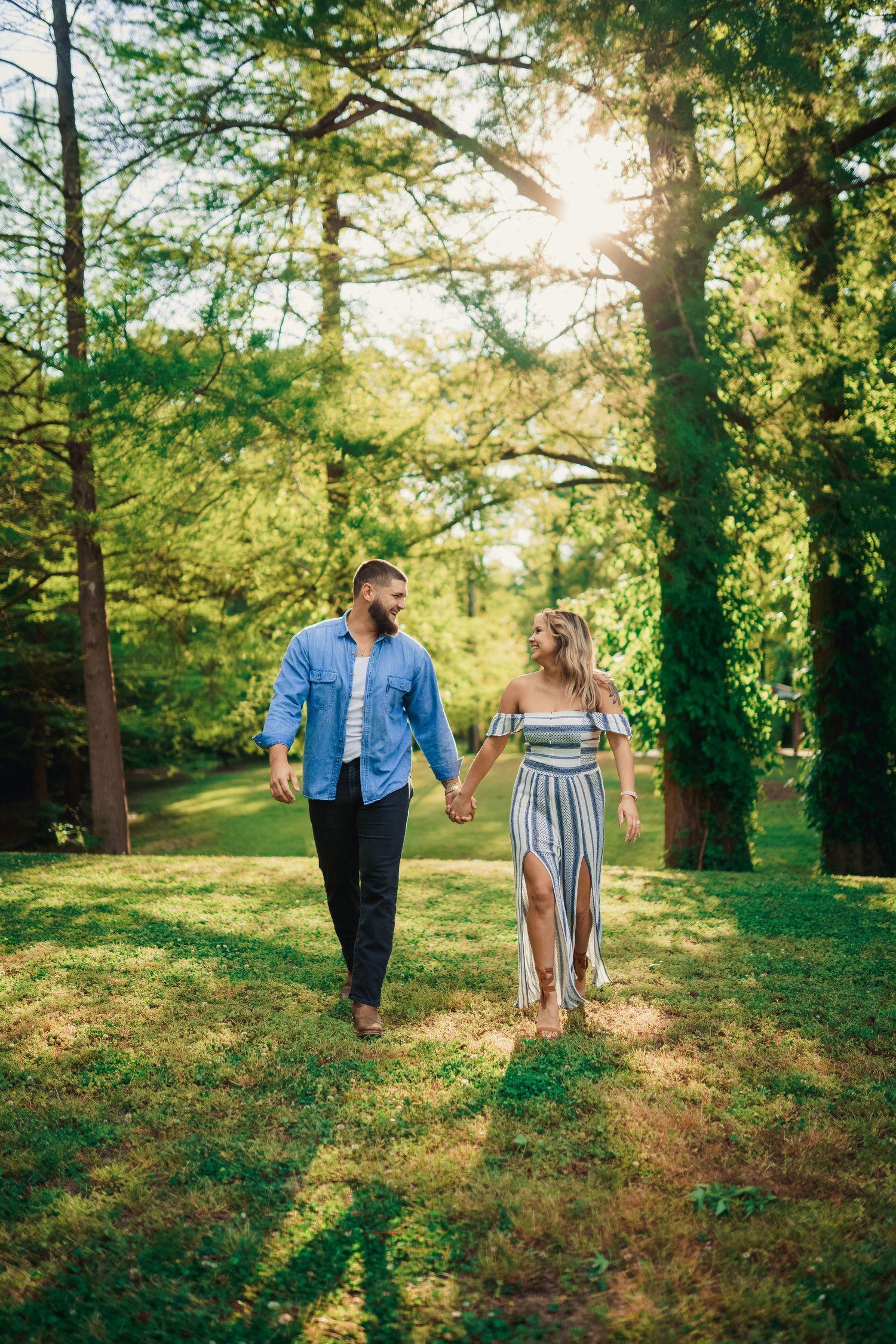 A couple holds hands while taking a walk through a lush green park on a sunny afternoon.