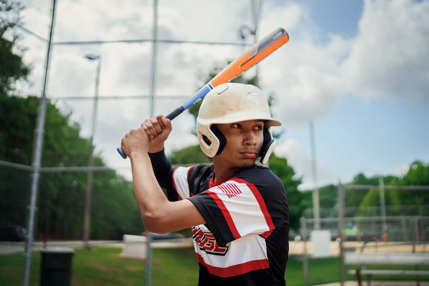 Youth baseball player in batting stance holds orange bat during practice.
