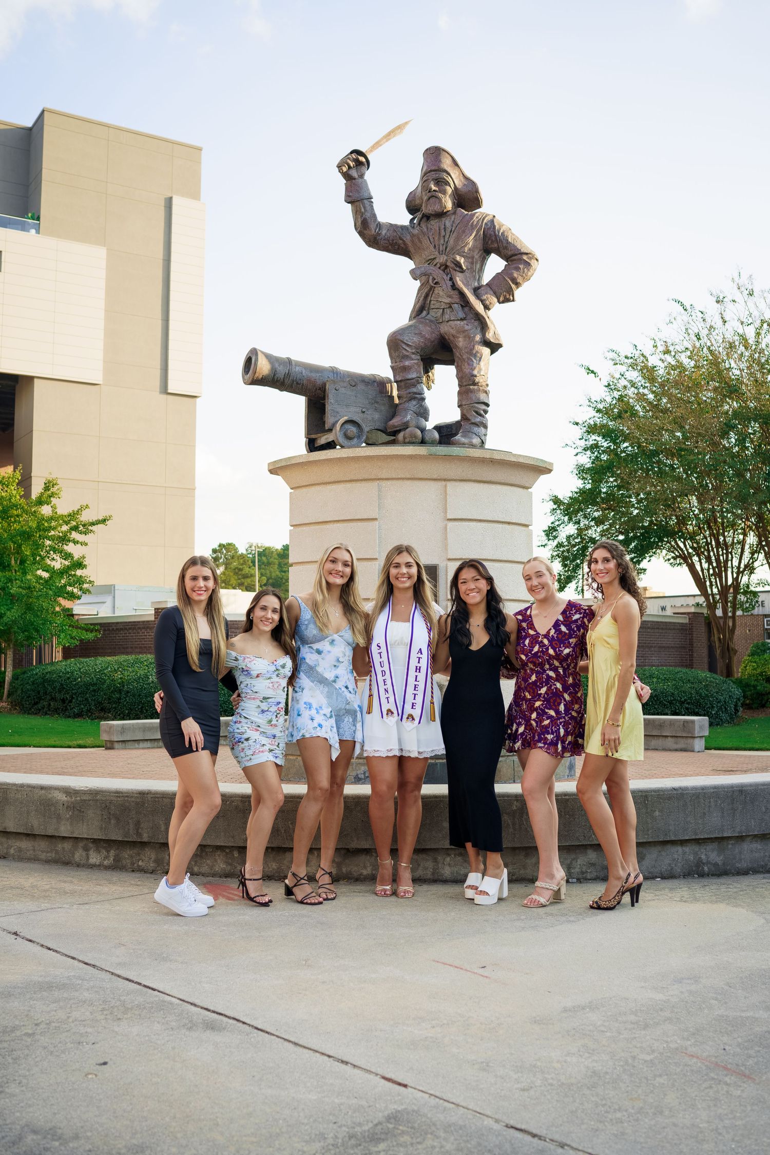 Group photo in front of a historical statue on a university campus.