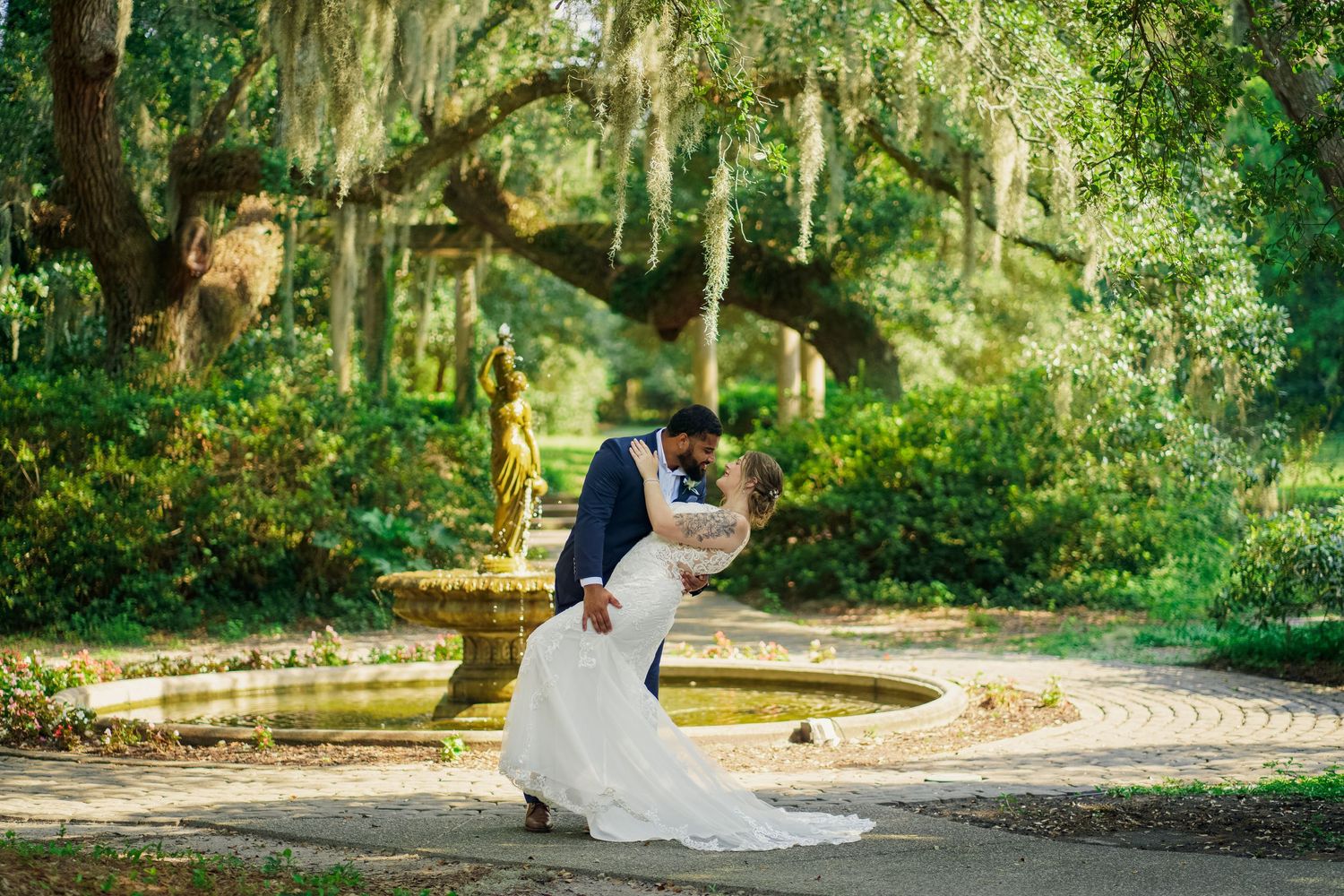 Couple dancing together during their wedding celebration in a garden setting with Spanish moss trees.