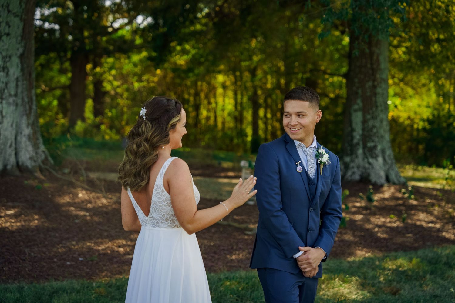 Newlyweds share an emotional moment during their first look in a wooded outdoor setting.