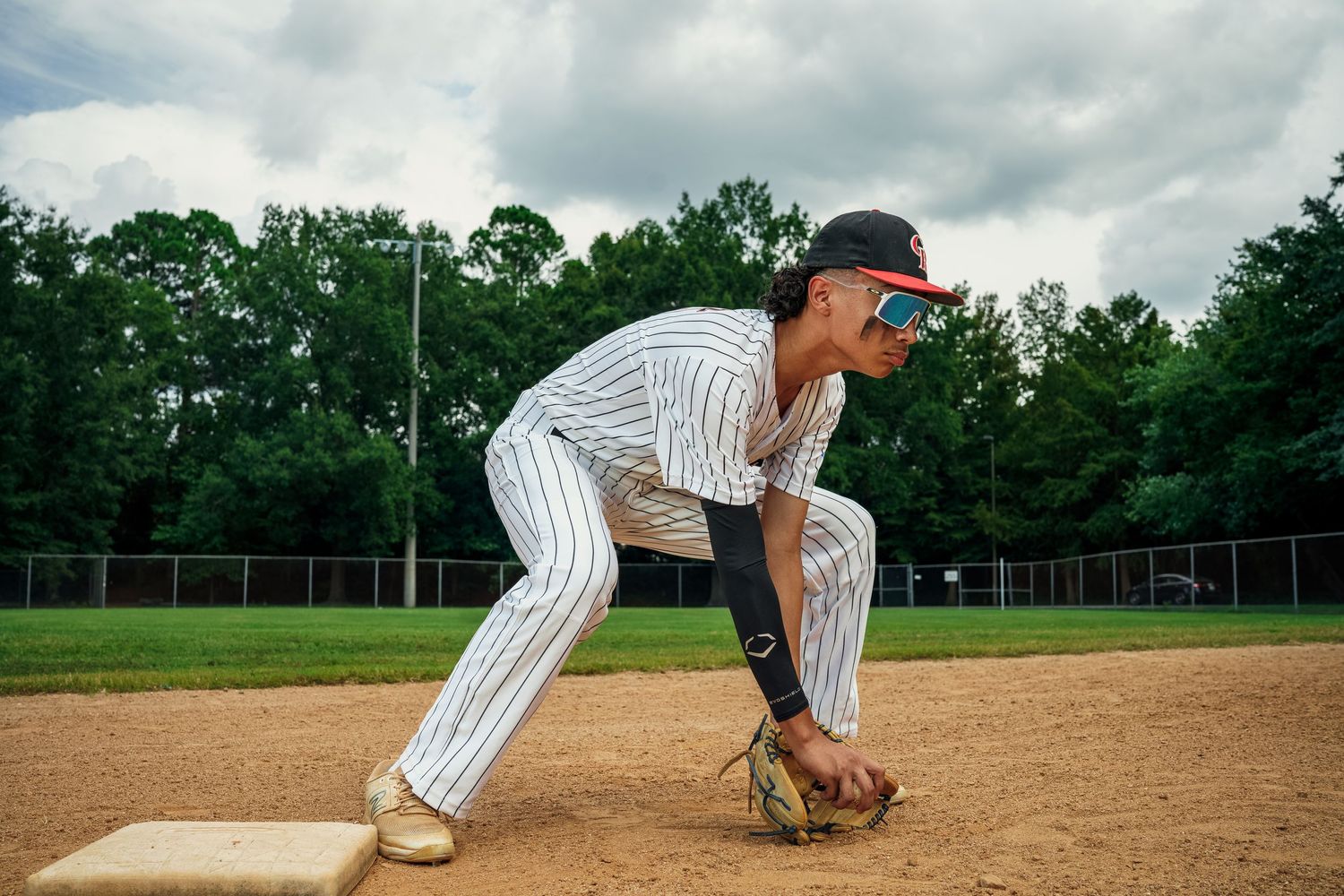 Baseball player in pinstripe uniform fields ground ball on infield dirt.