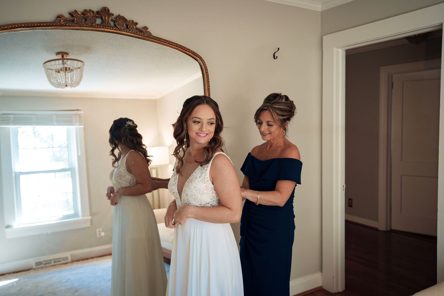 Wedding preparations underway with bridesmaids helping with final touches in an elegant room.