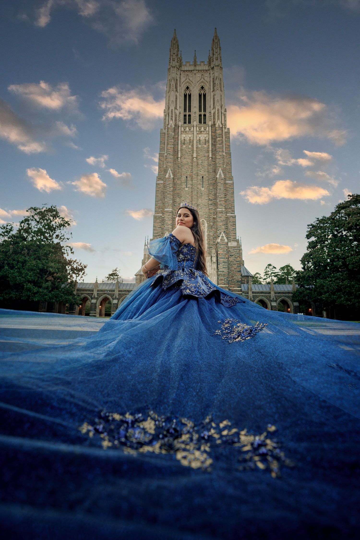 Dramatic blue ballgown dress photographed against gothic cathedral architecture during golden hour sunset.