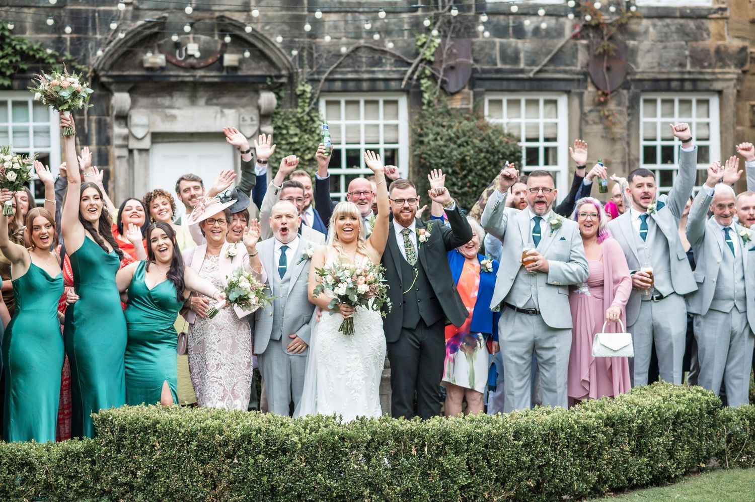 Large wedding party in coordinated attire celebrating outside historic building.
