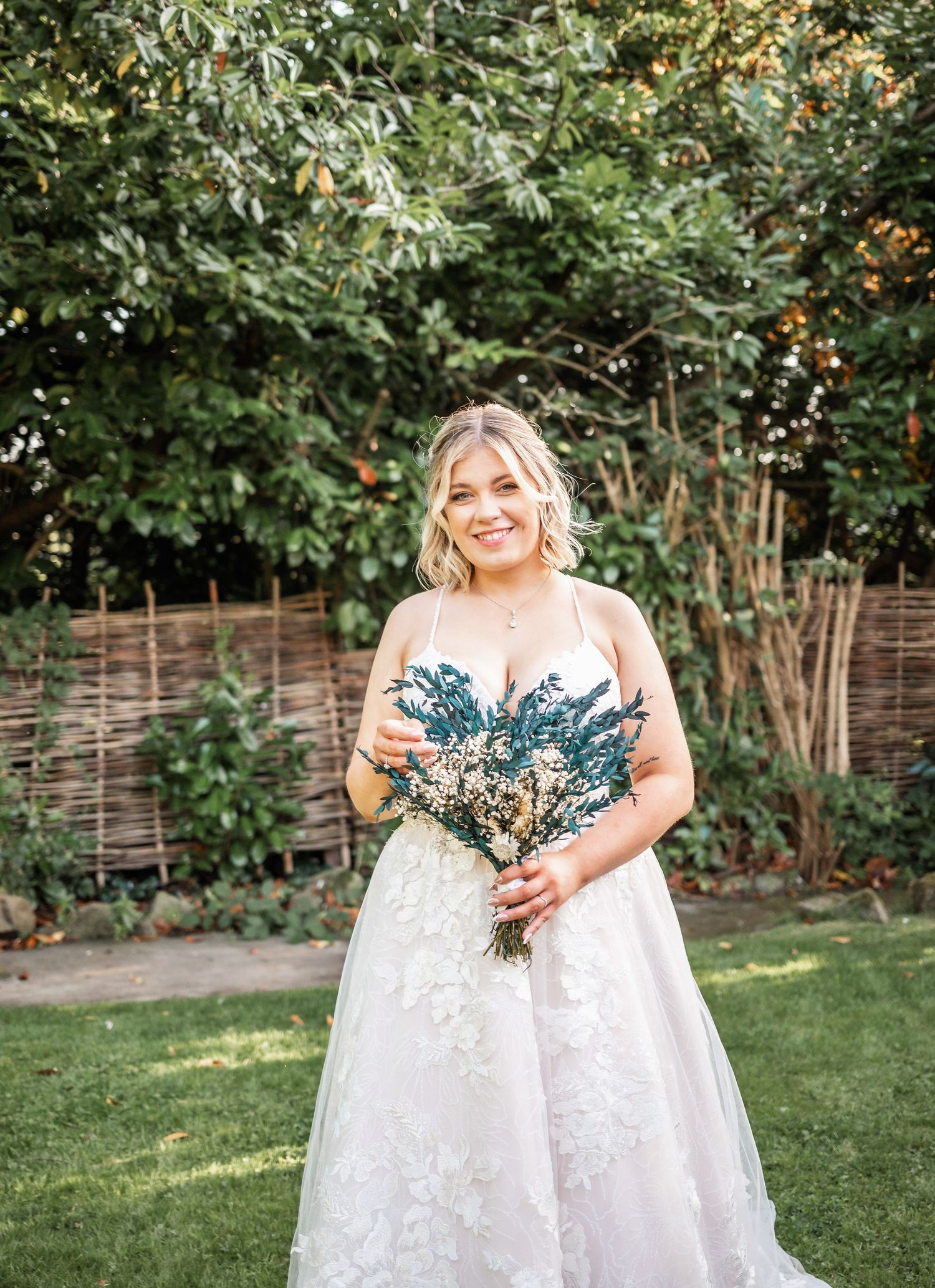 A wedding portrait in a garden setting with natural greenery and sunlight.