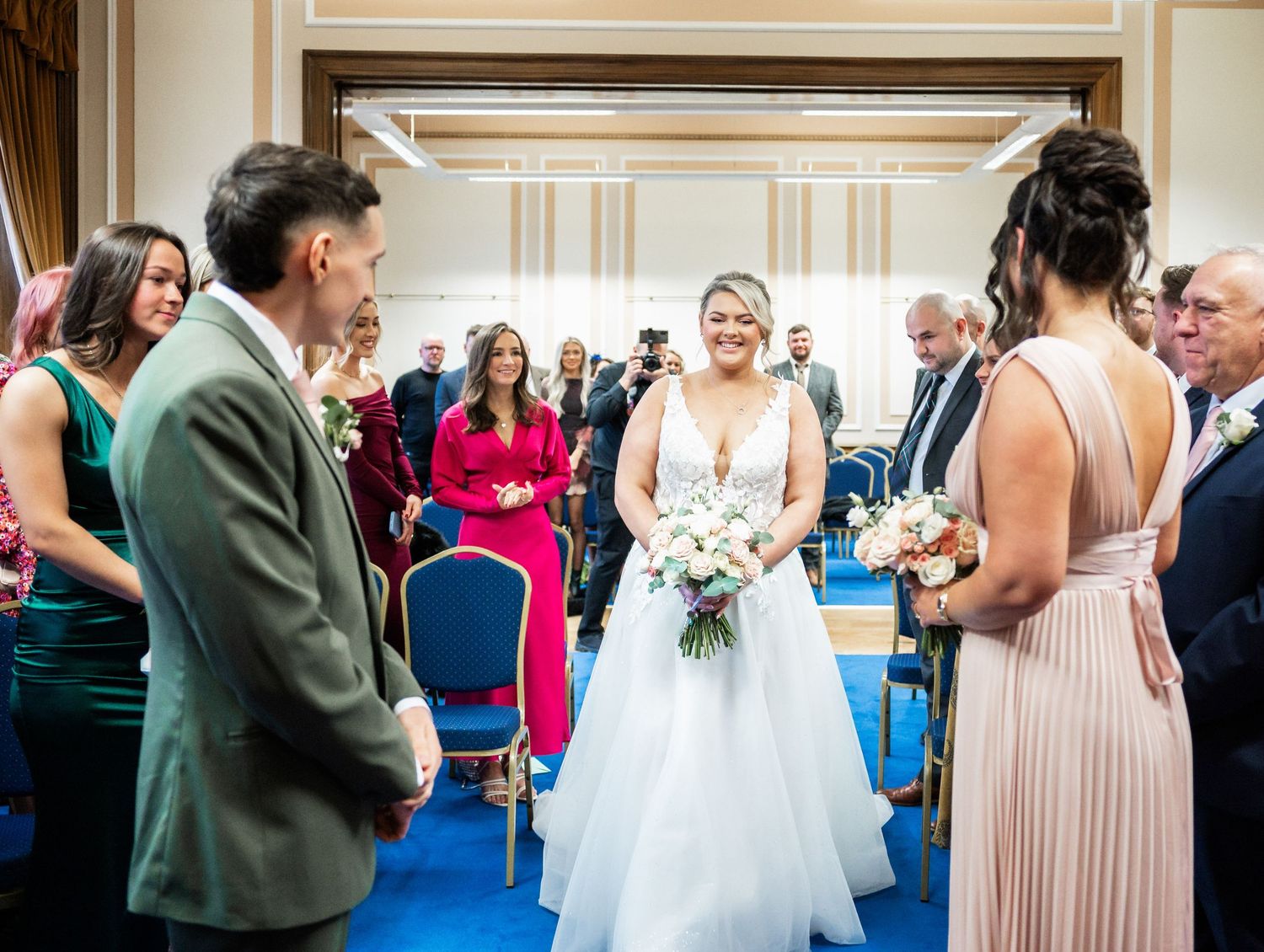 Wedding ceremony in an elegant indoor venue with guests gathered around in formal attire.