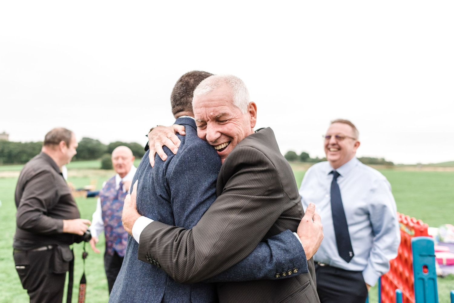 Emotional embrace between two guests at outdoor celebration.