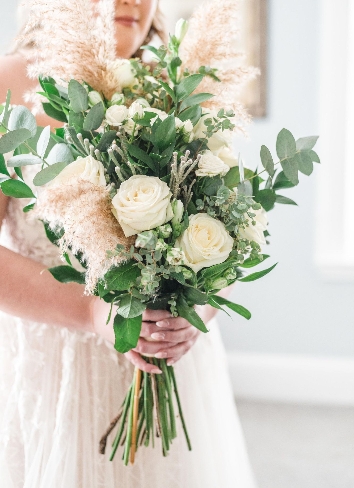 Elegant bridal bouquet featuring white roses, eucalyptus, and pampas grass.