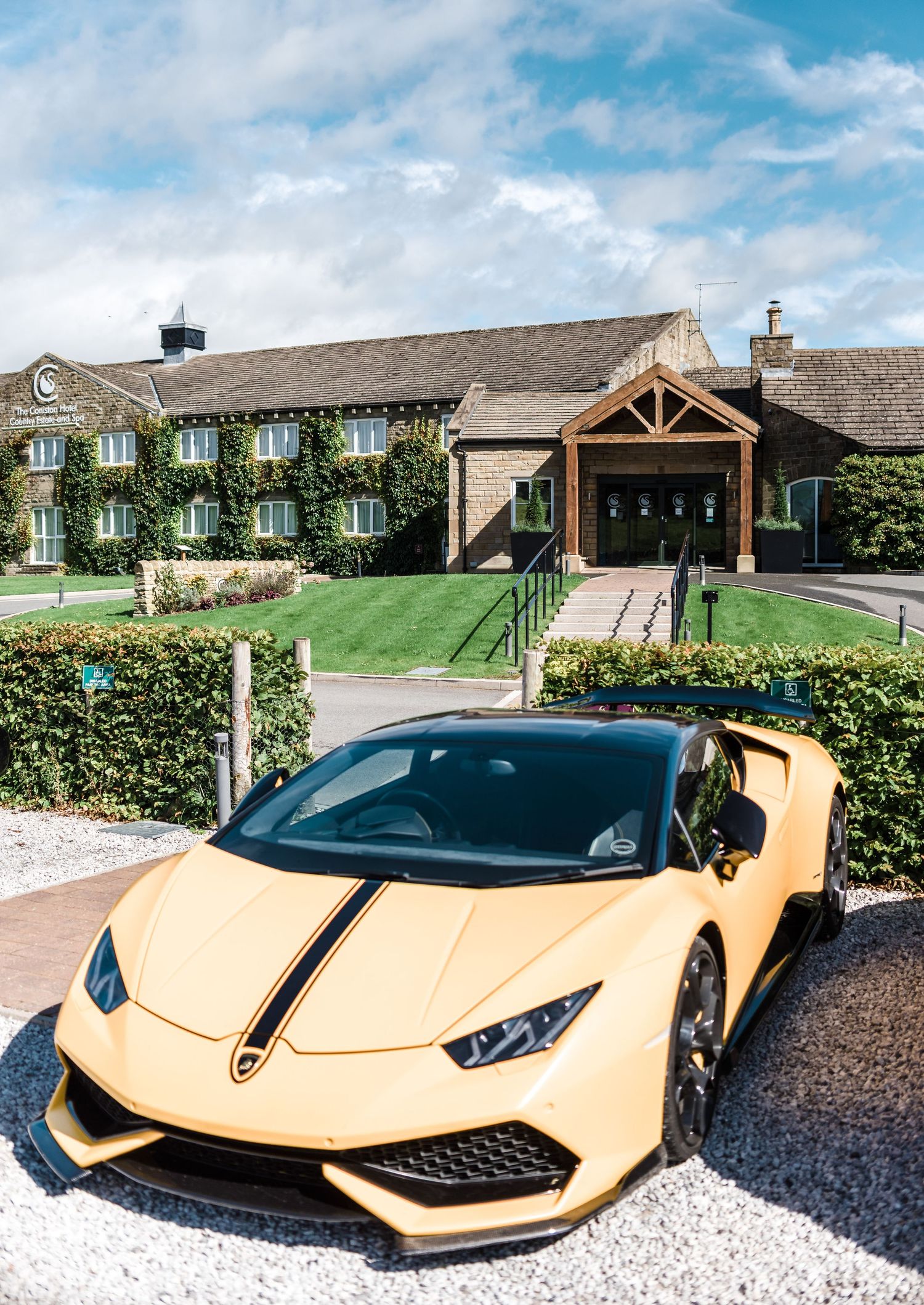 Yellow Lamborghini parked outside ivy-covered wedding venue with timber entrance.