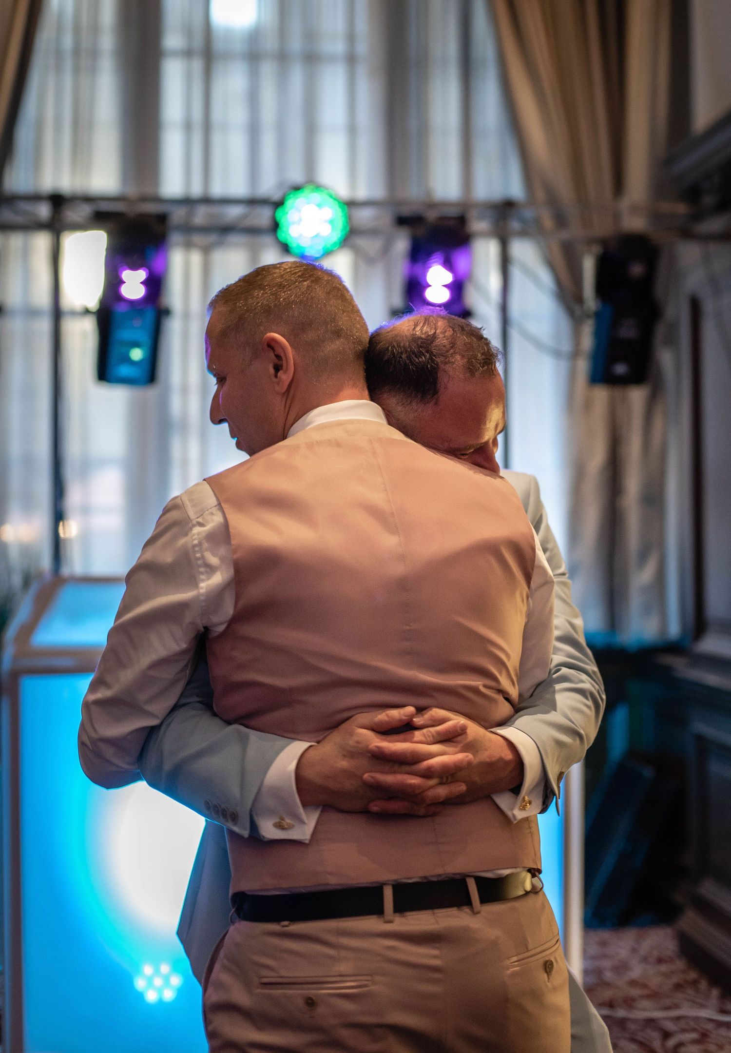 A couple shares an intimate slow dance under blue and purple stage lights.