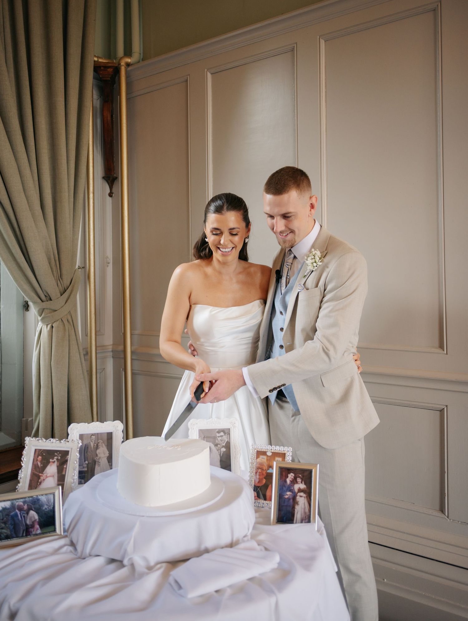 Newlyweds share a playful moment in an elegant room with grey paneled walls.