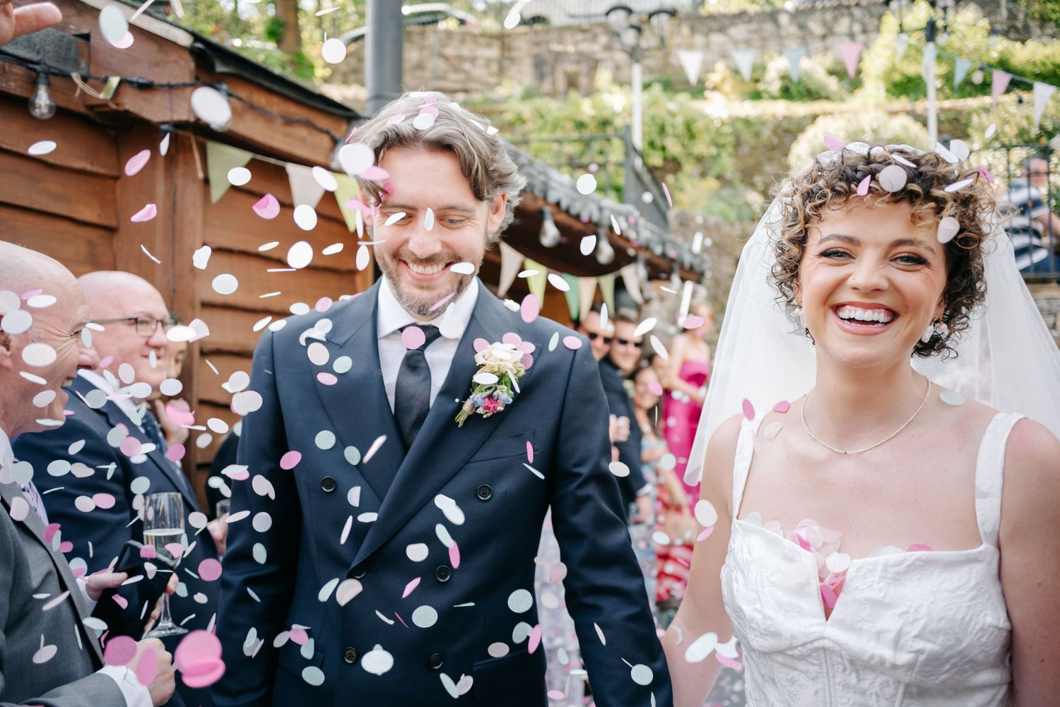 Joyful wedding celebration with flower petals being tossed in the air.