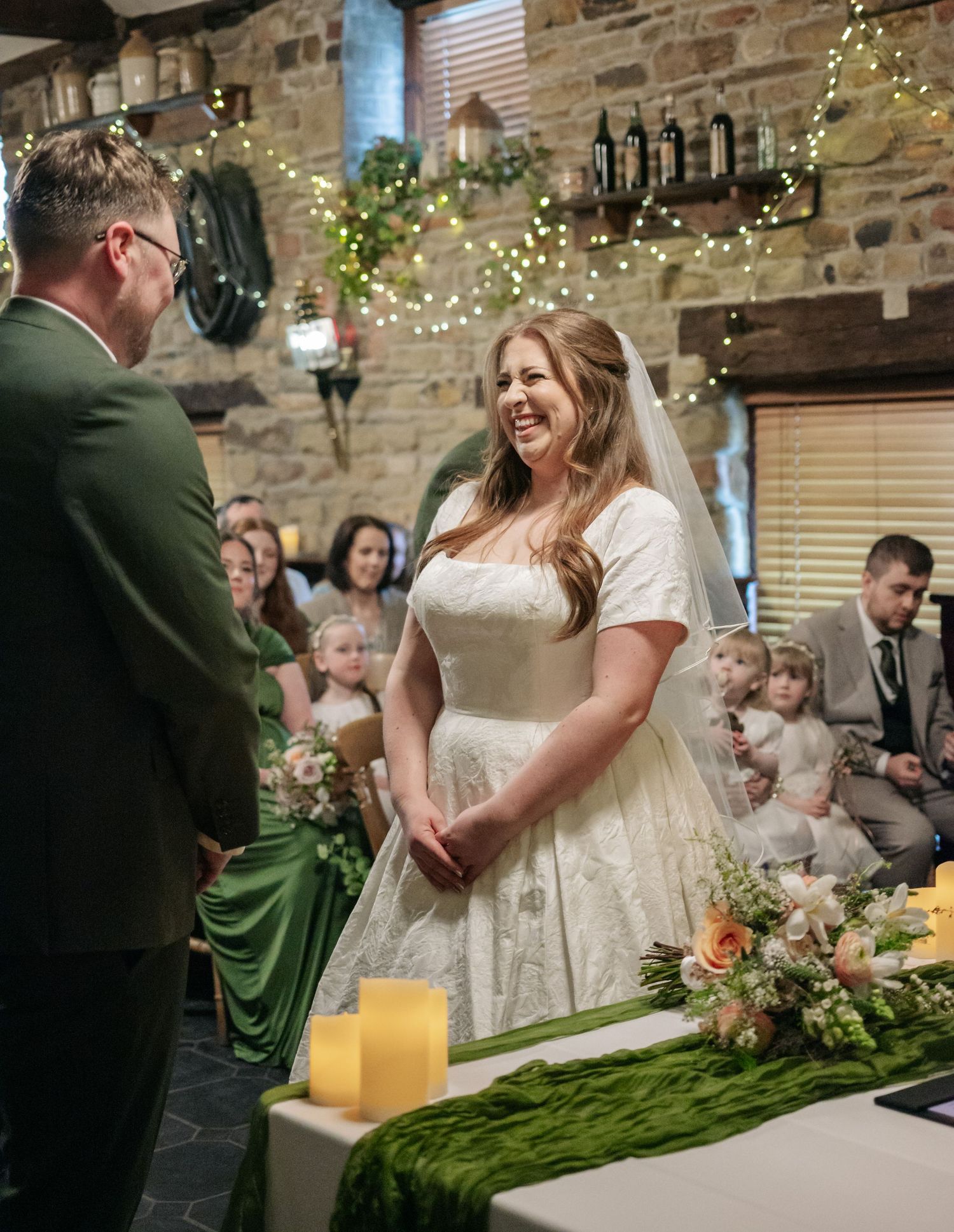 Wedding ceremony in a rustic stone venue with twinkle lights and floral decorations.