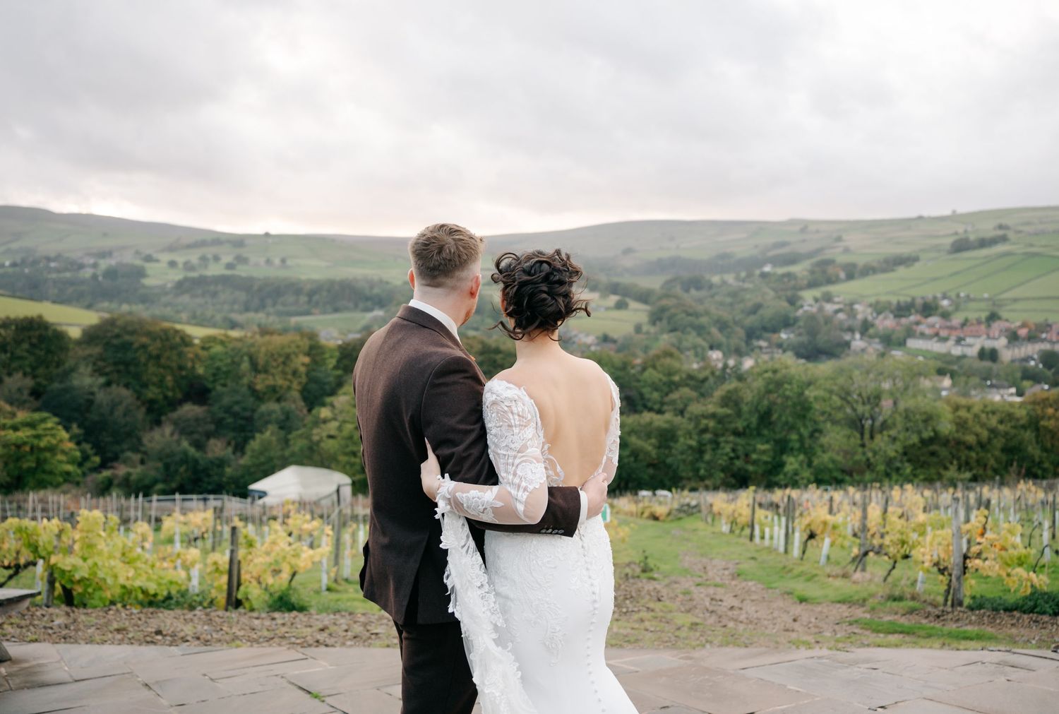 Romantic wedding couple portraits against a scenic countryside vineyard backdrop.