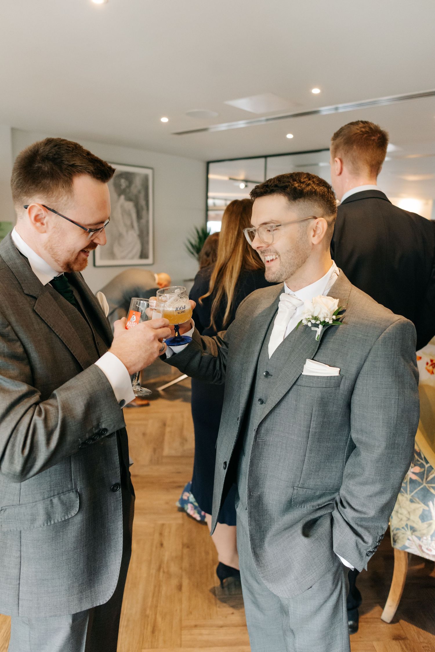 Groomsmen in gray suits share laughs and conversations during pre-wedding preparations.
