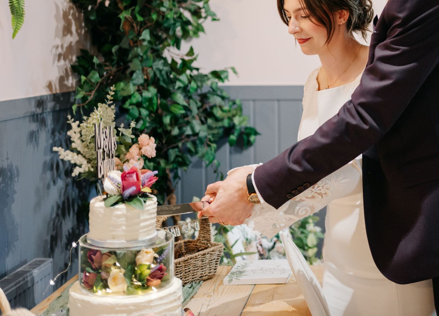 A wedding cake being cut by a couple with a silver cake knife at an elegant reception.