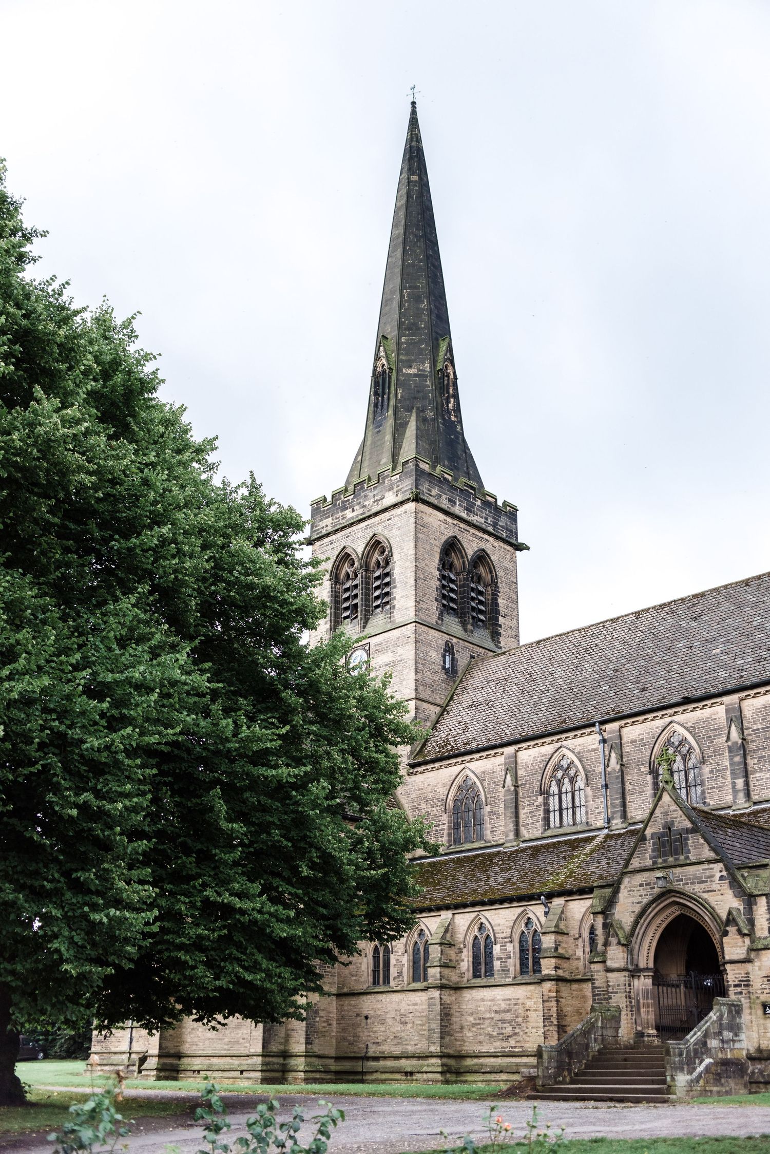 A historic stone church with tall spire and Gothic architecture against an overcast sky.