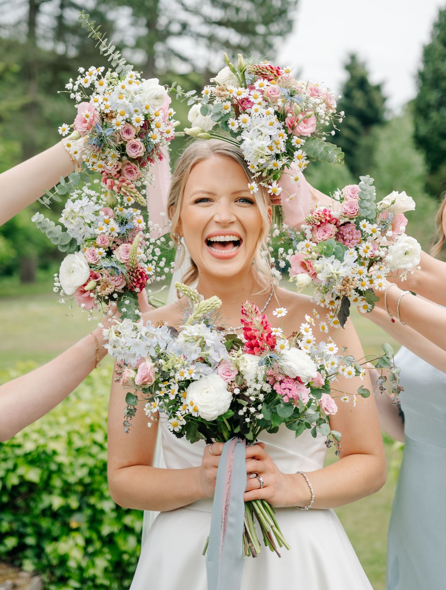 Wedding flowers frame a joyful portrait in a garden setting with pink and white blooms.