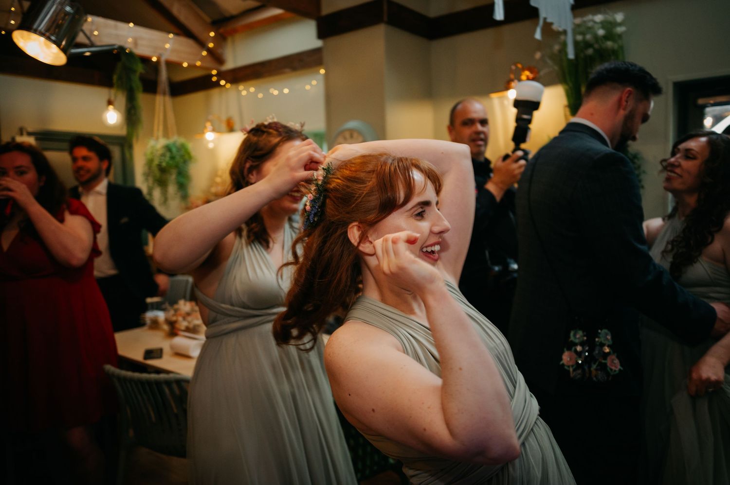 Wedding reception party guests dancing and celebrating under indoor lighting.