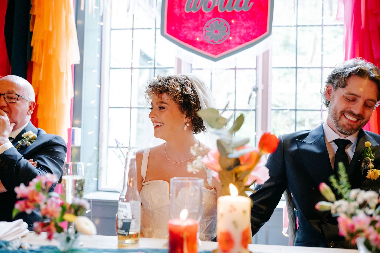 Wedding reception scene with decorative lighting and floral centerpieces in elegant indoor venue.