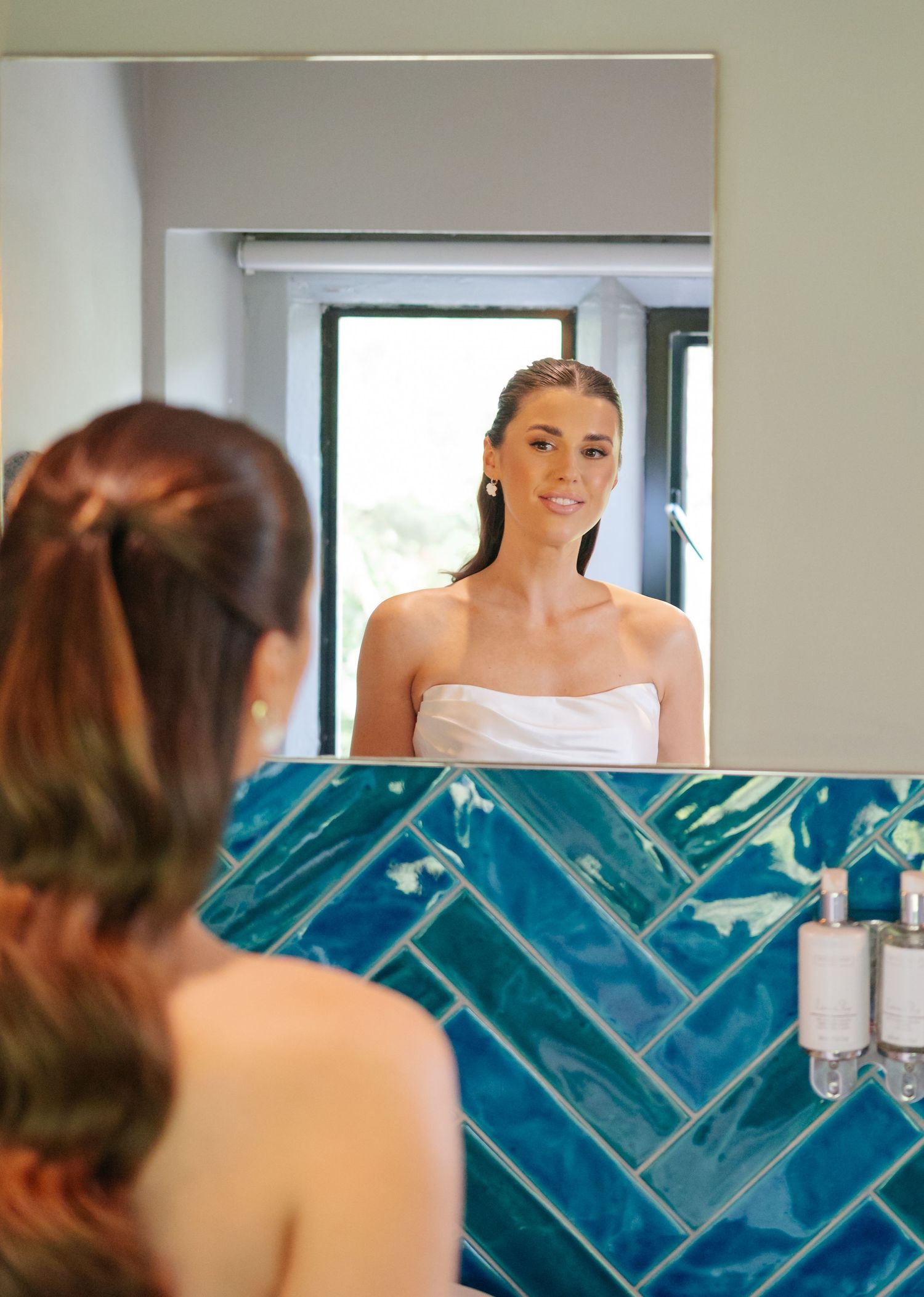 Wedding preparation scene with blue tiled mirror reflections and white attire.