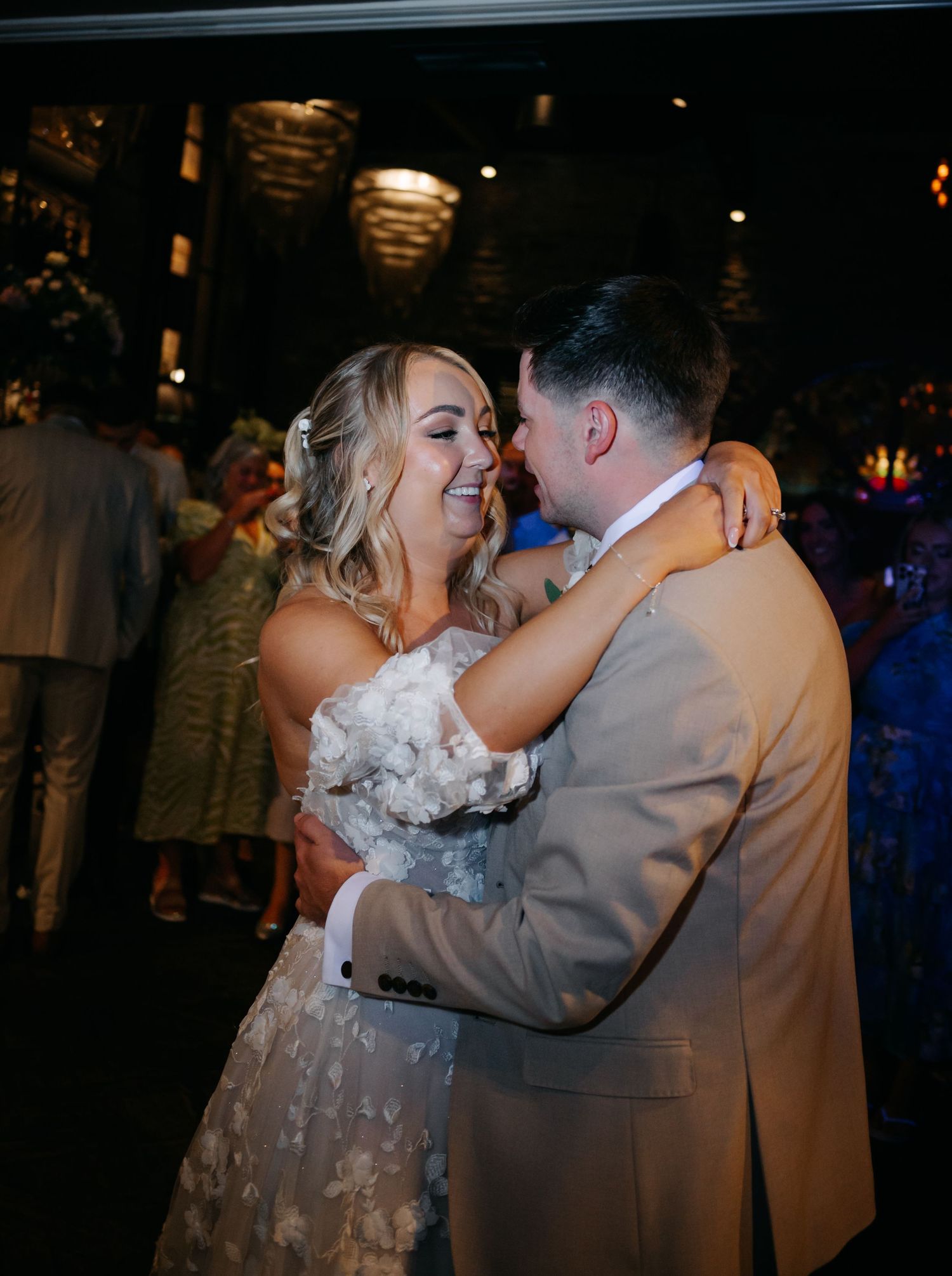 Couple shares joyful dance moment at wedding reception with ambient lighting and decorative elements.