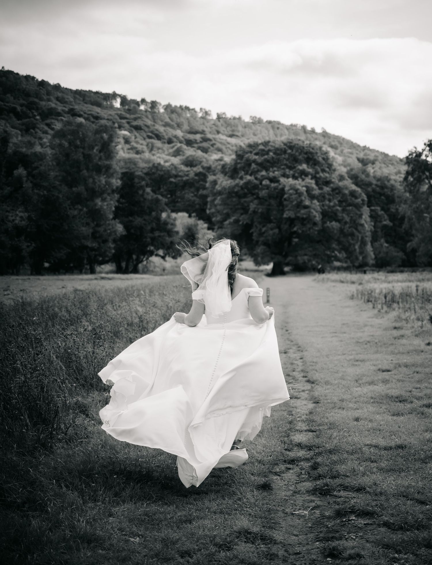 A flowing white dress billows dramatically in the wind across a series of black and white landscape photographs.