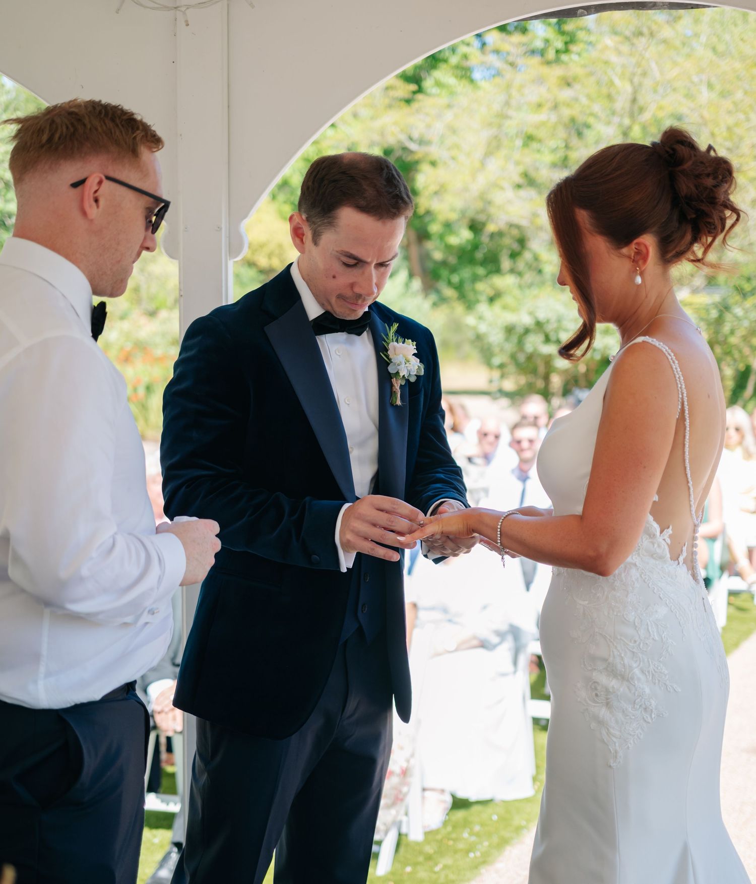Wedding ceremony sequence showing ring exchange between couple in outdoor setting.