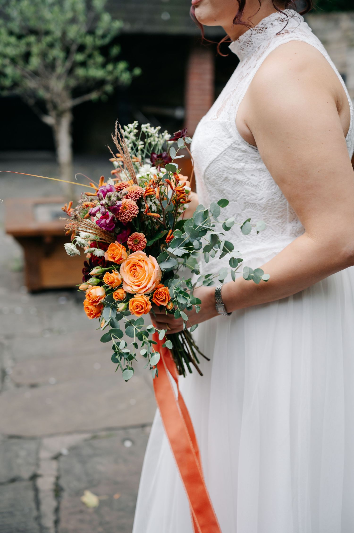 Close-up shots of a bridal bouquet featuring orange roses and greenery with matching ribbon.