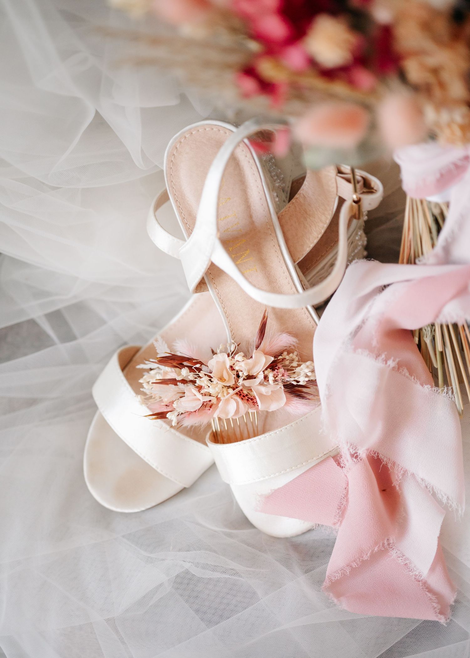 Delicate pink and white ballet shoes with ribbons and tulle arranged in a romantic wedding detail shot.