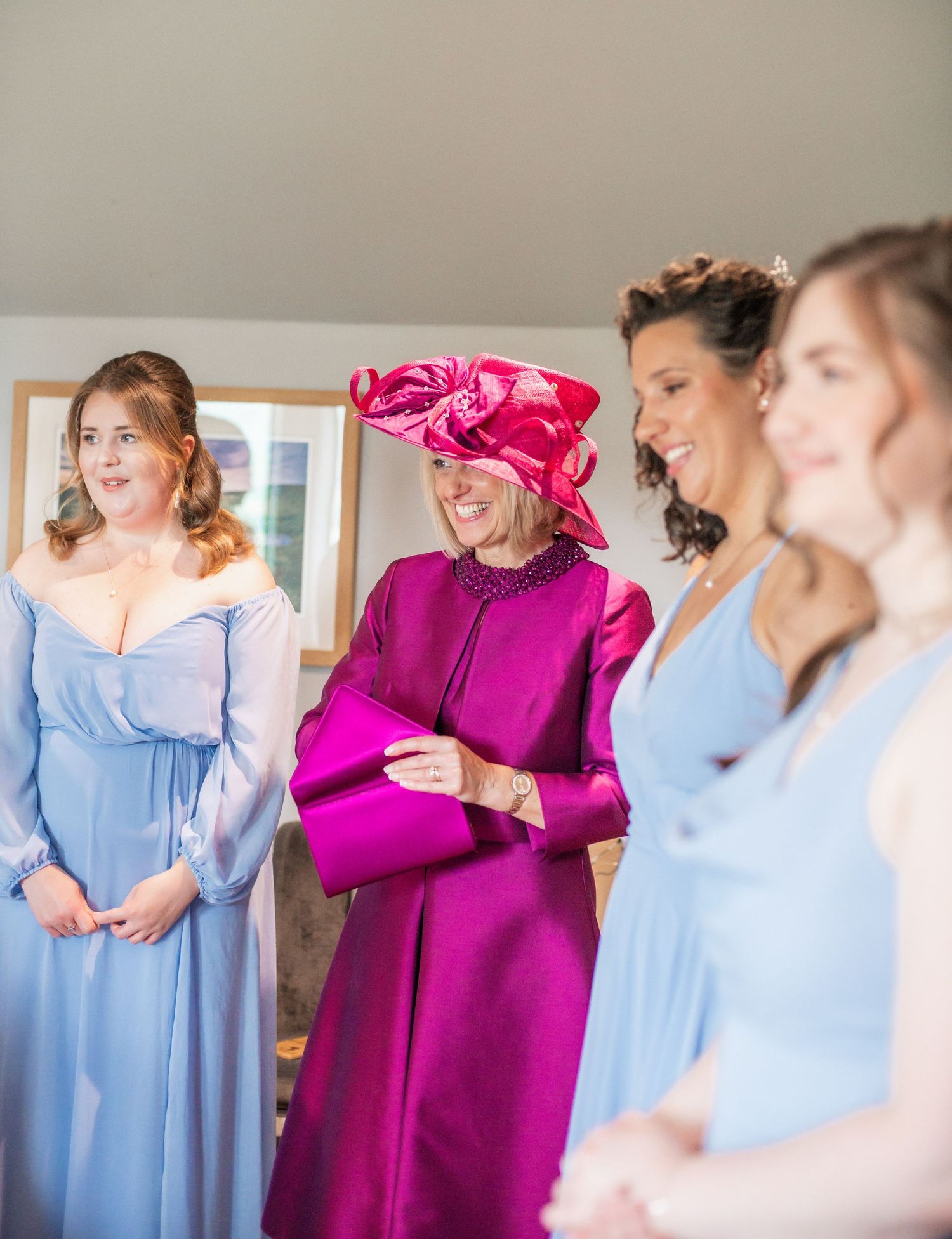 Wedding party members in blue dresses with a guest in vibrant magenta attire.