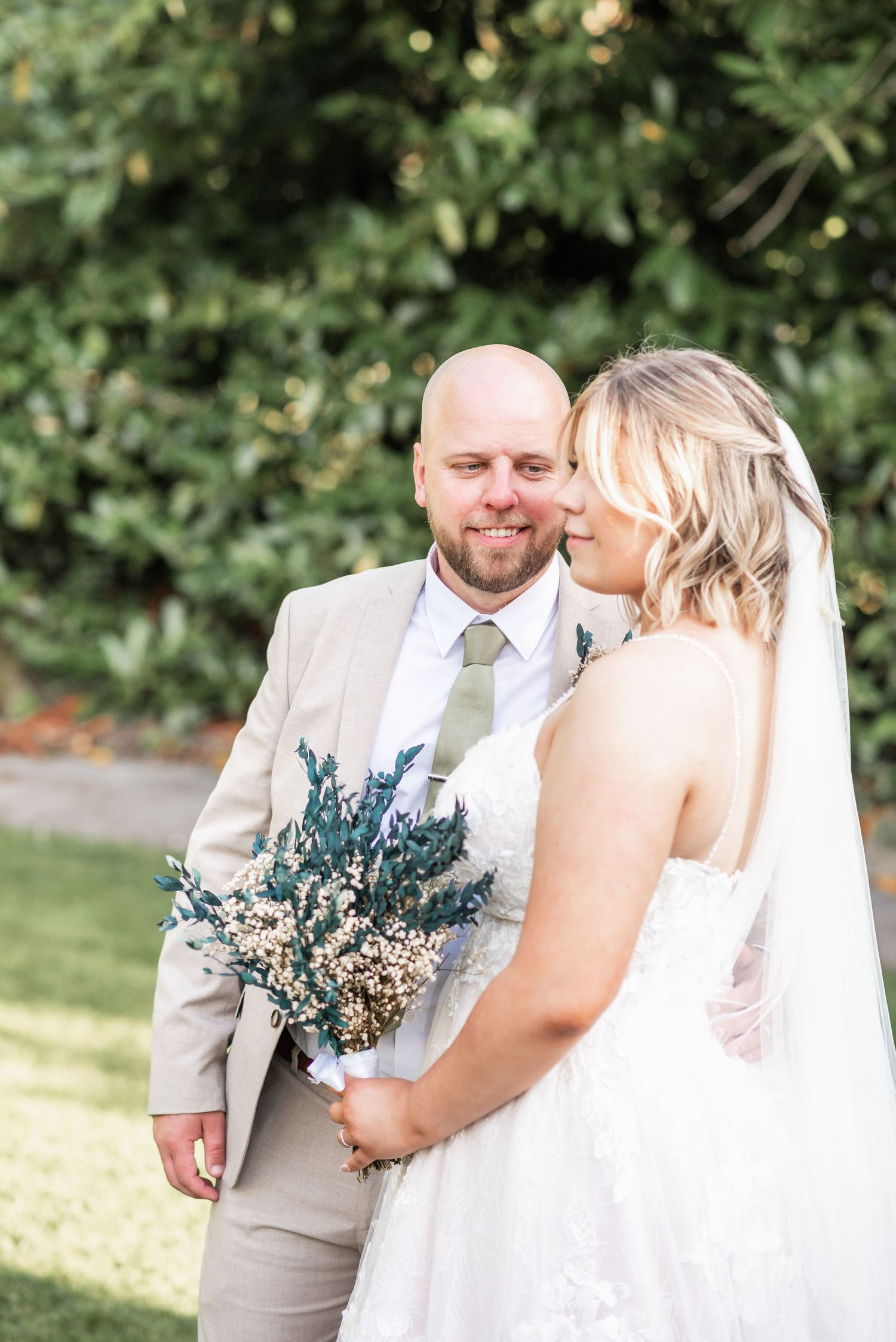 A tender moment captured between a couple in a garden setting with natural greenery.