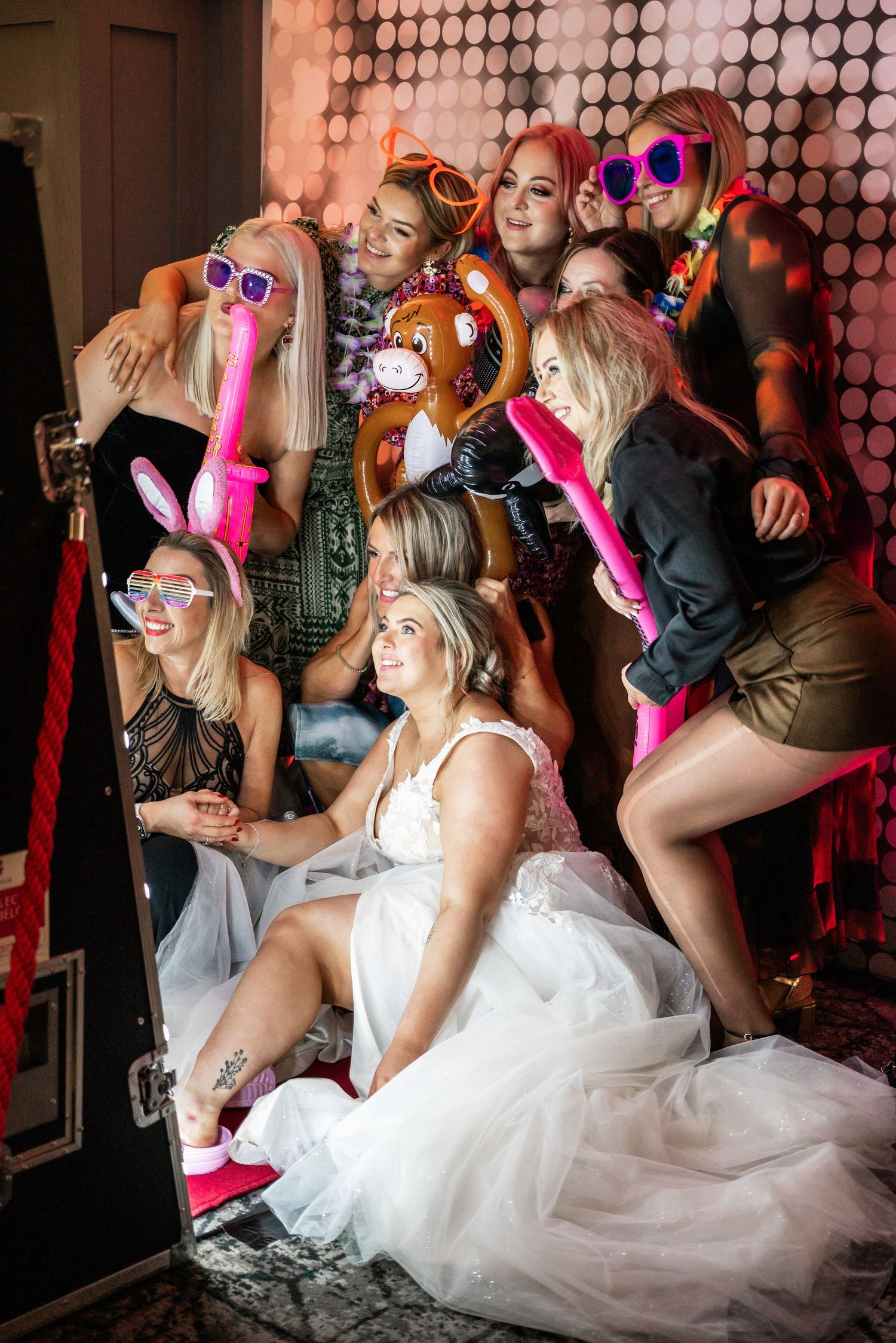 Wedding party posing with fun props and sunglasses against a sparkly backdrop.