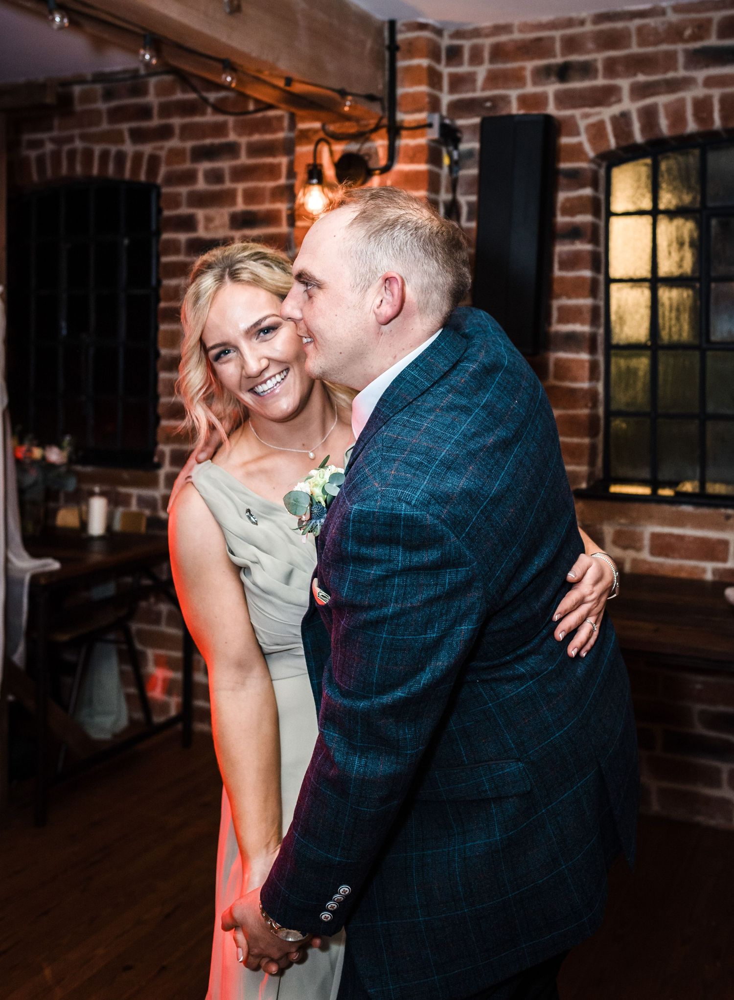 Couple sharing an intimate dance moment at wedding reception with exposed brick backdrop.