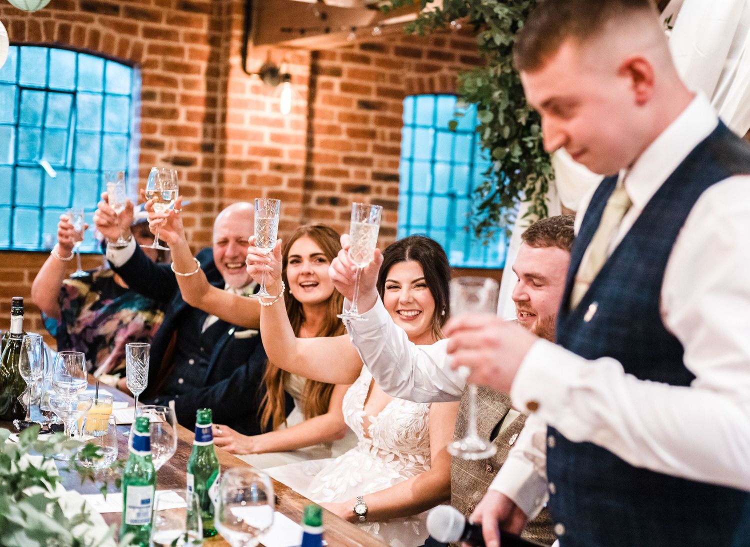 Wedding guests raising glasses for a toast during reception celebration.