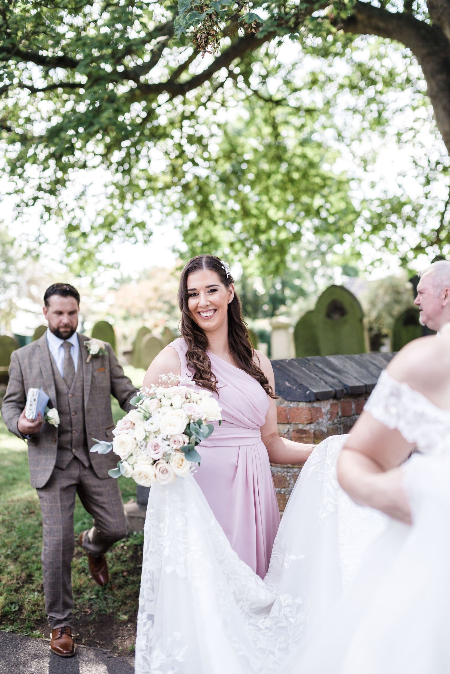 Wedding party gathered outdoors near stone church wall.