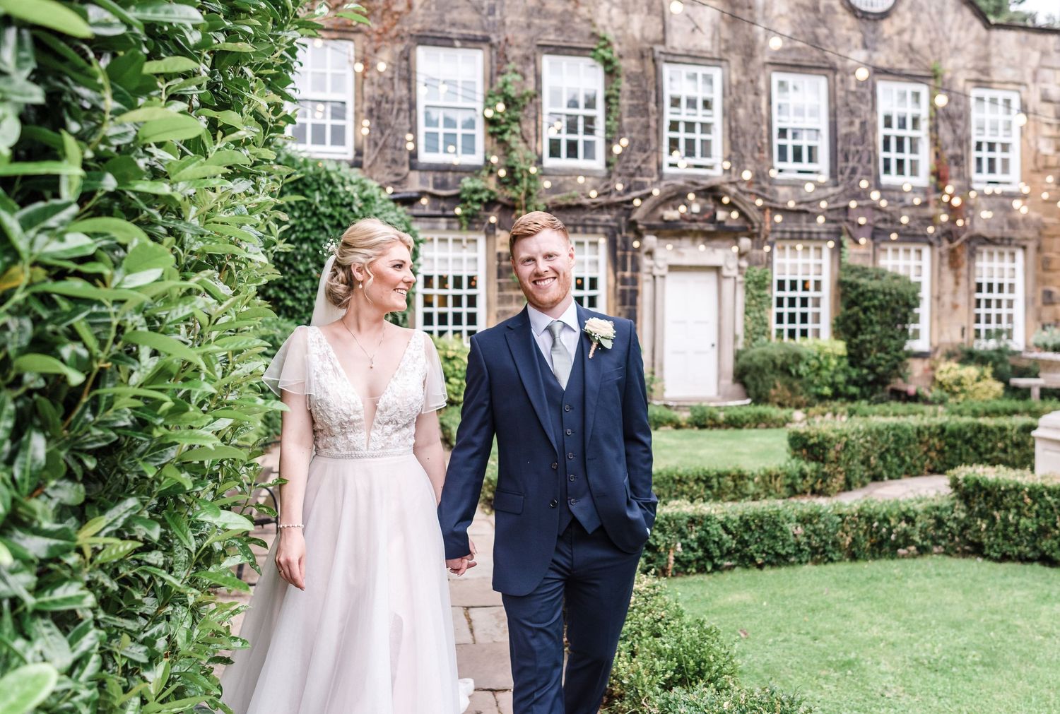 Couple walking together outside historic brick building with ivy covered walls.
