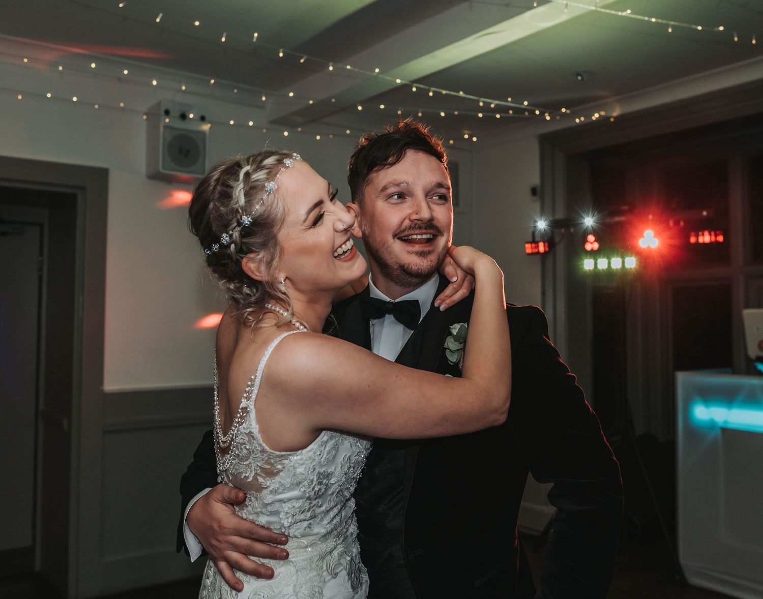 Dancing moment at wedding reception under romantic string lights.