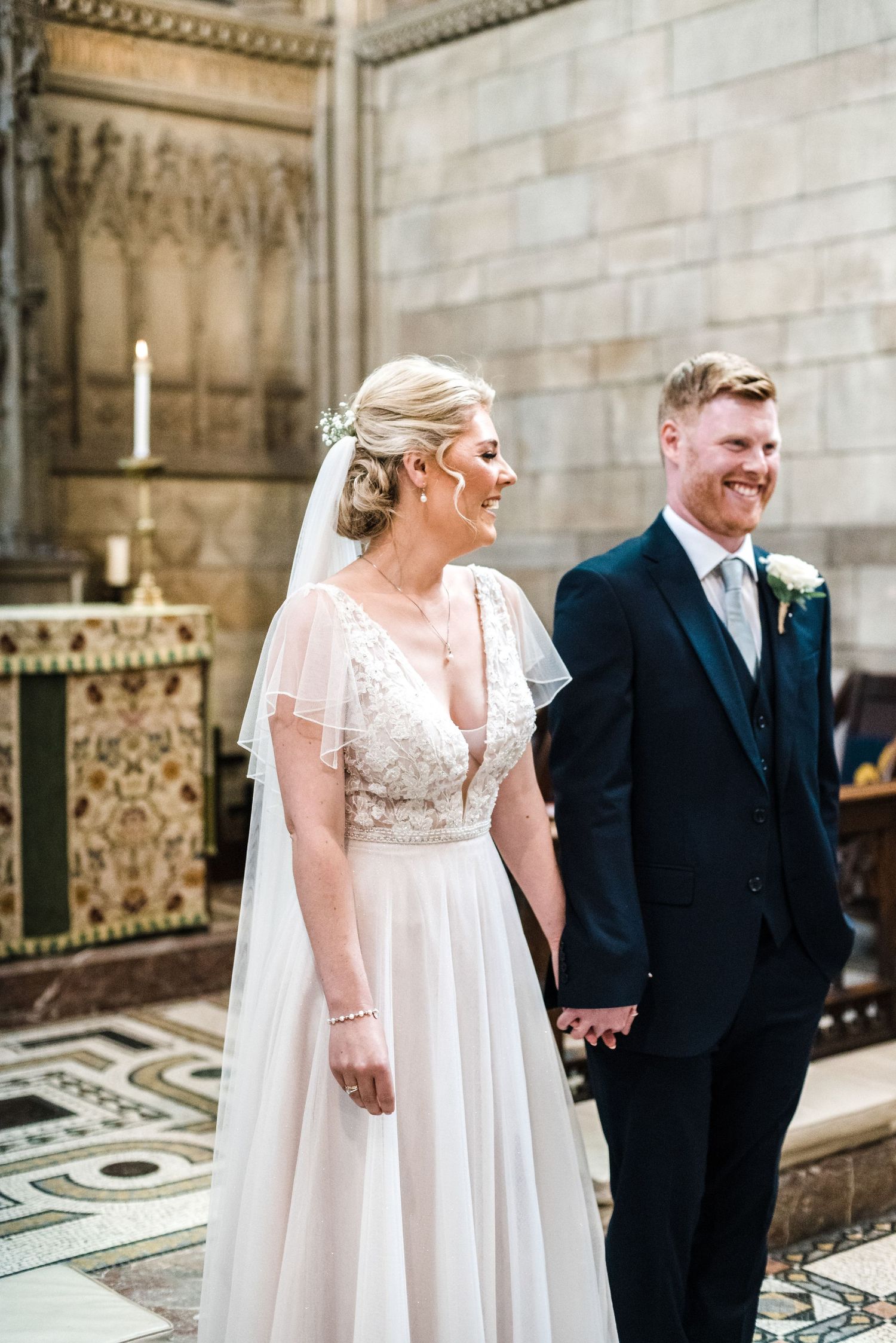 A couple shares a joyful moment together inside an ornate church during their wedding ceremony.