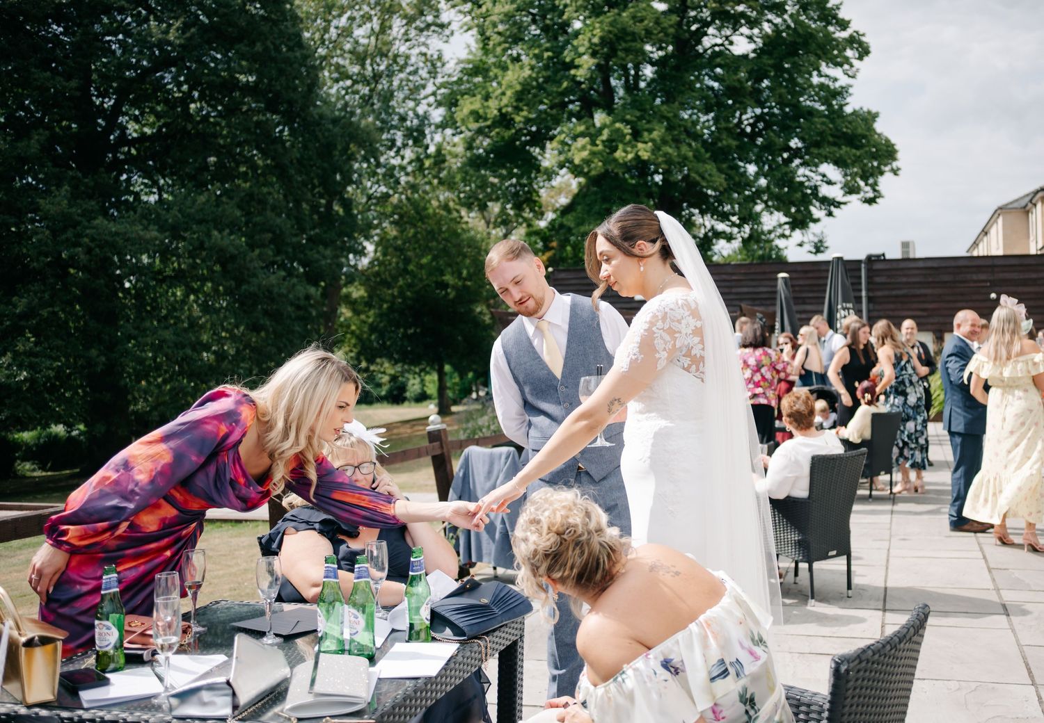 Outdoor wedding celebration with guests mingling on stone patio area.