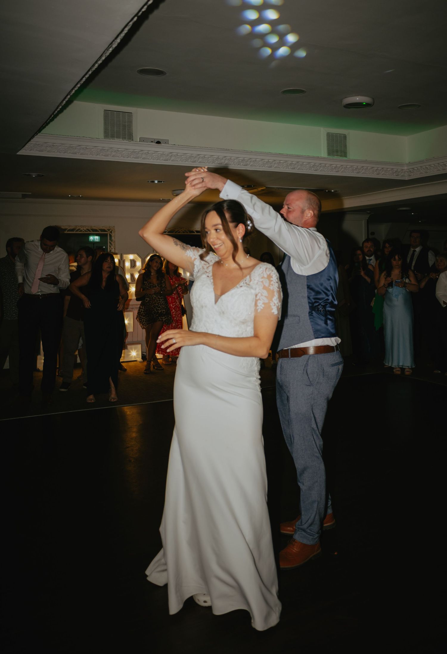 Couple dancing together at their wedding reception in a dimly lit ballroom.