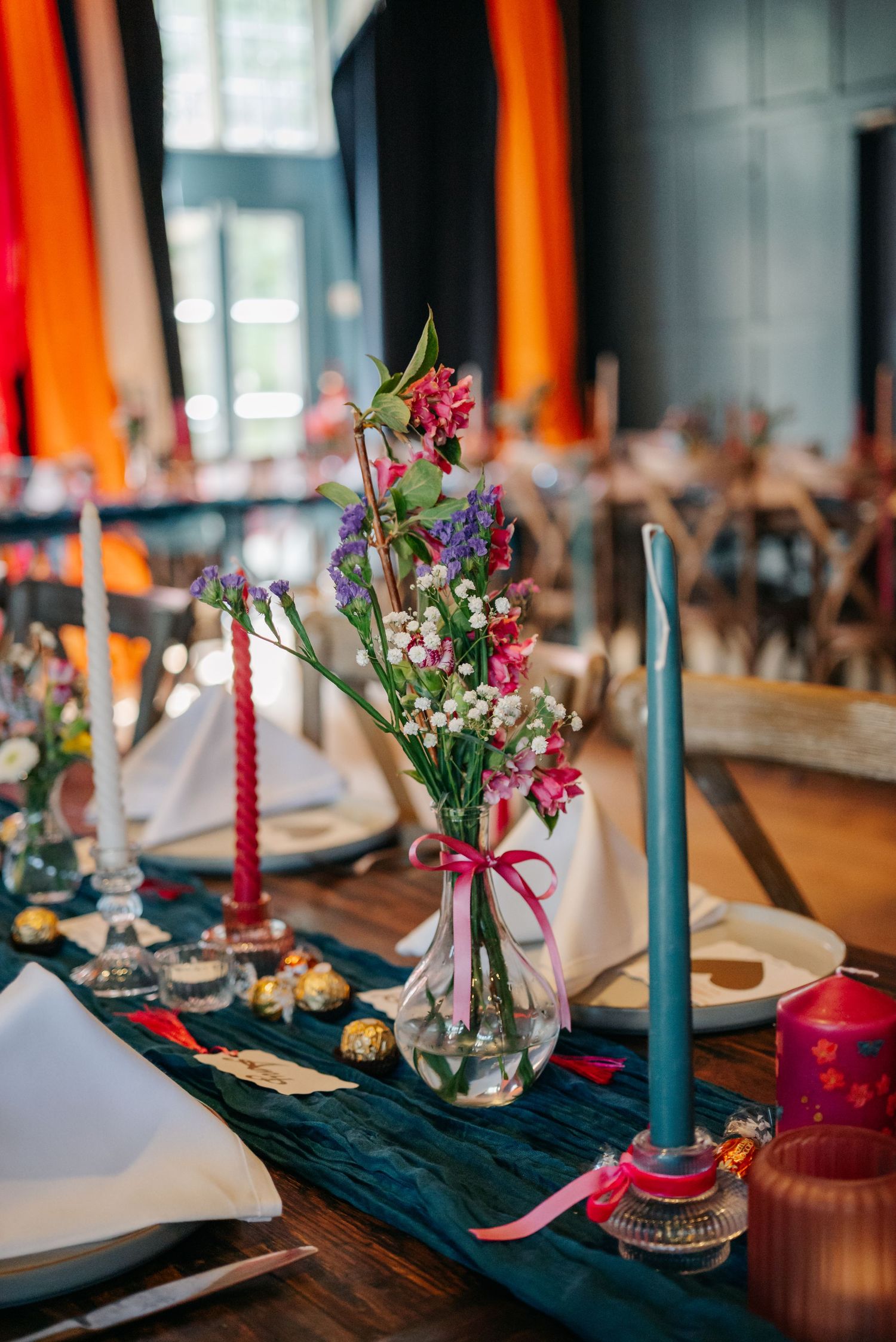 Elegant table setting with blue candles and colorful floral centerpieces.