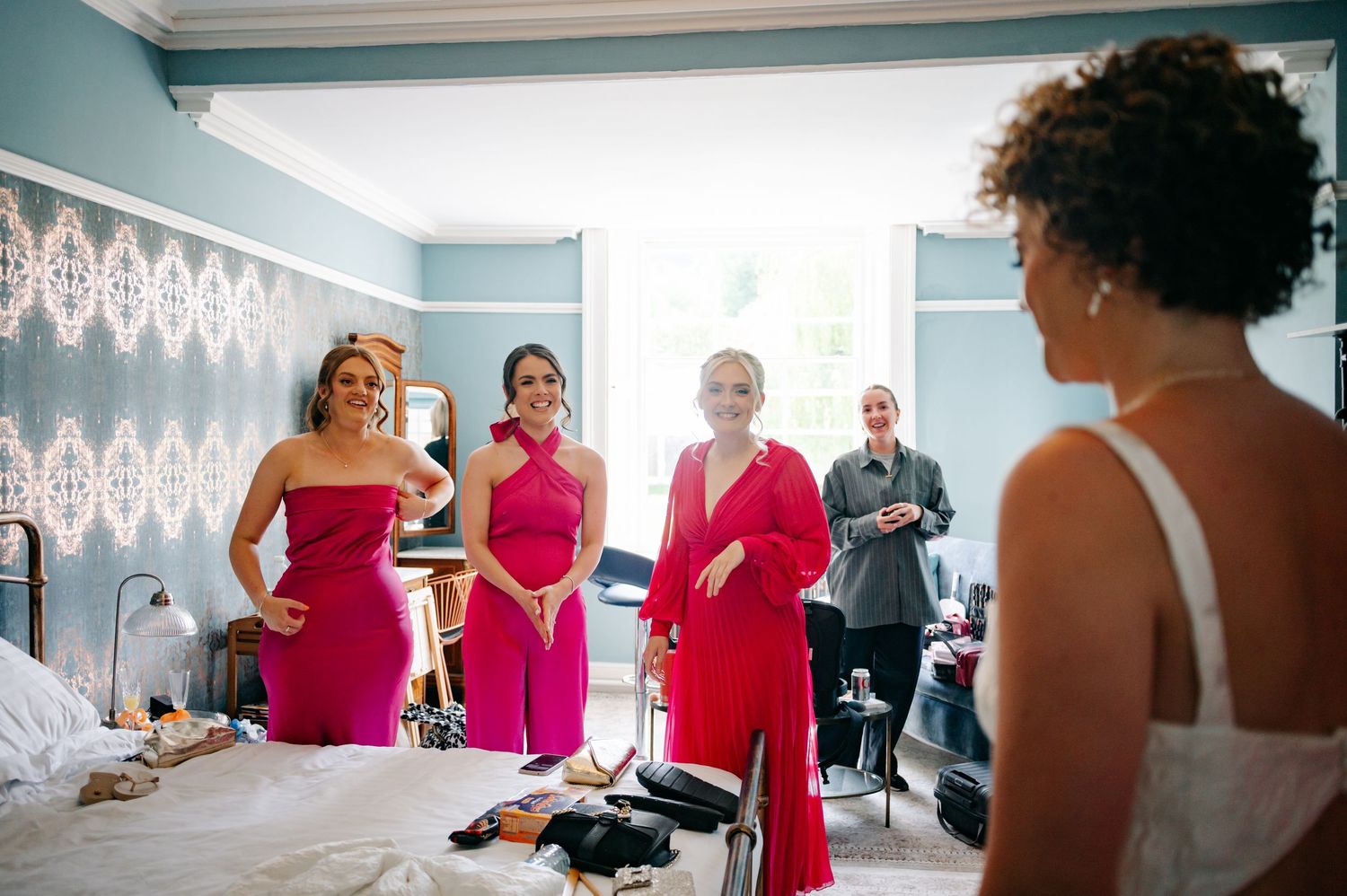 Wedding party members in bright pink dresses gather in preparation for the ceremony.