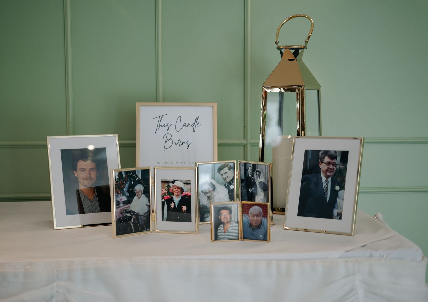 A row of framed family photographs displayed on a mint green wall.