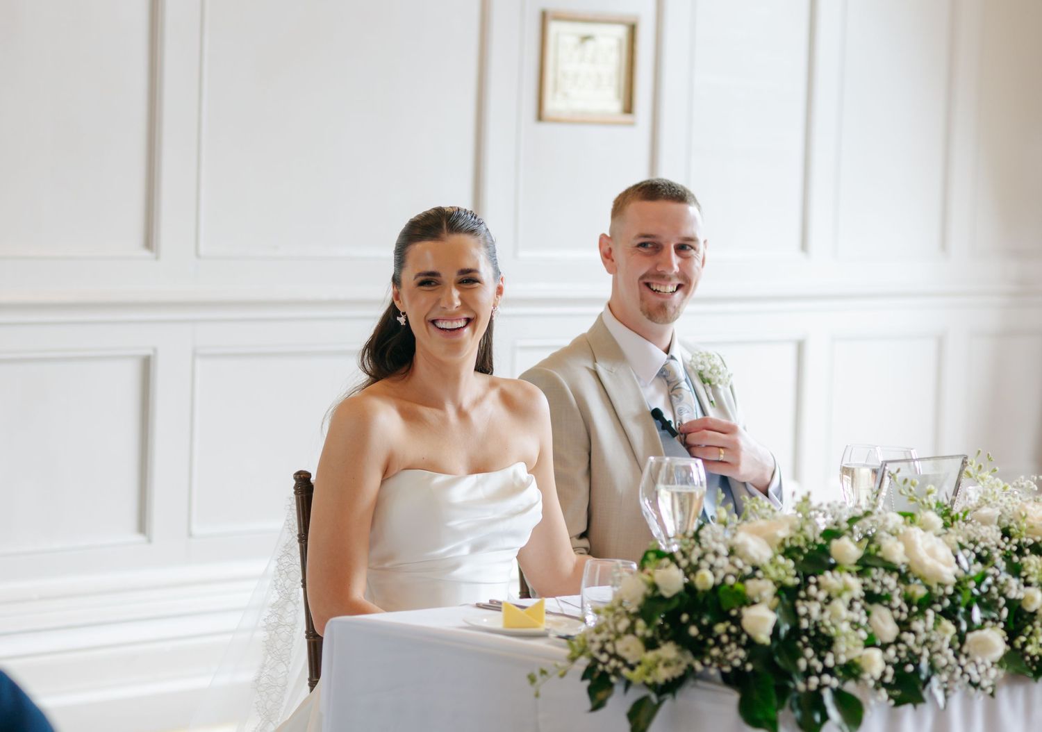 Wedding reception table decorated with elegant white floral arrangements and place settings.