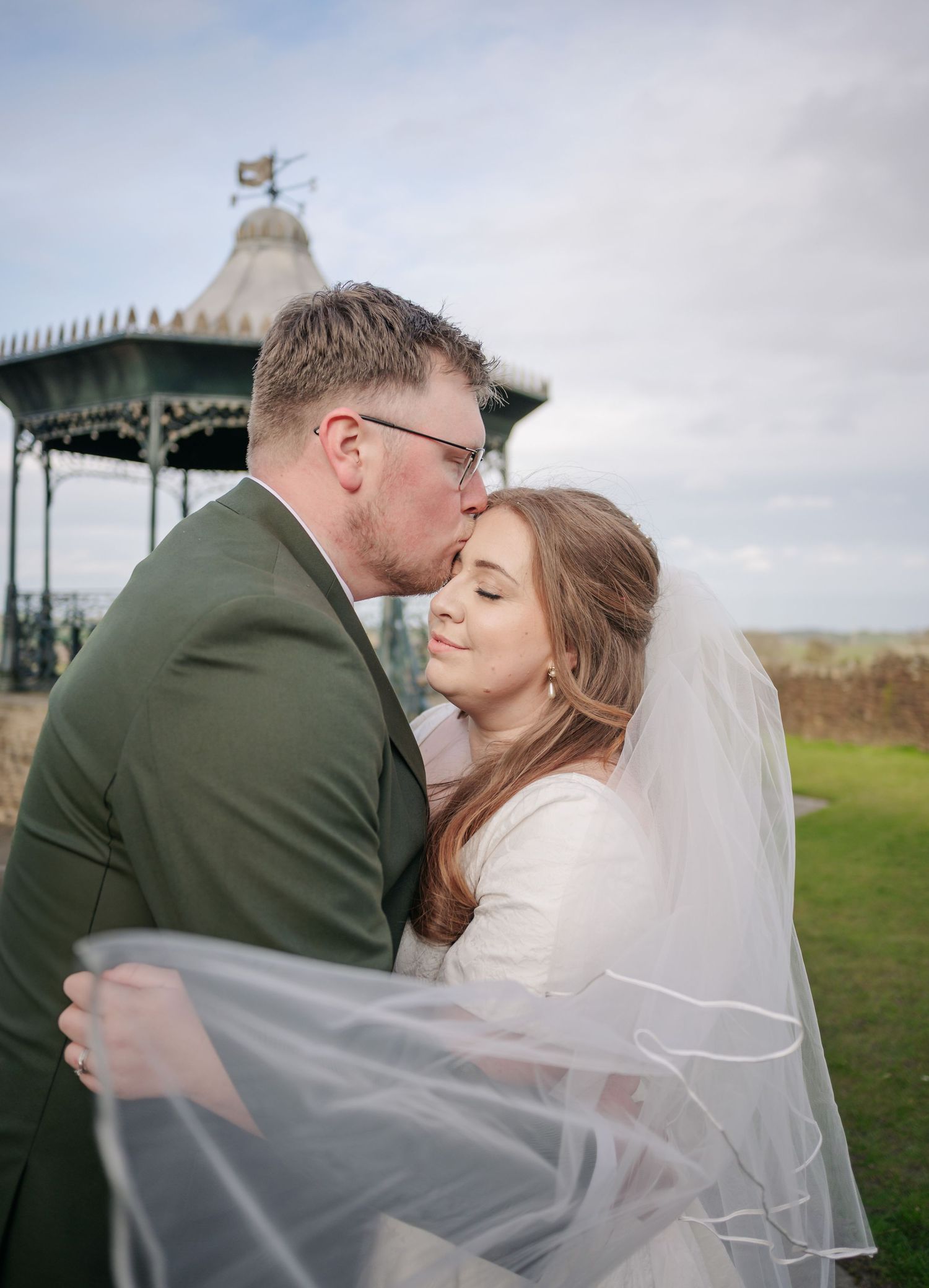 A romantic moment between newlyweds as the bride's veil flows in the wind.